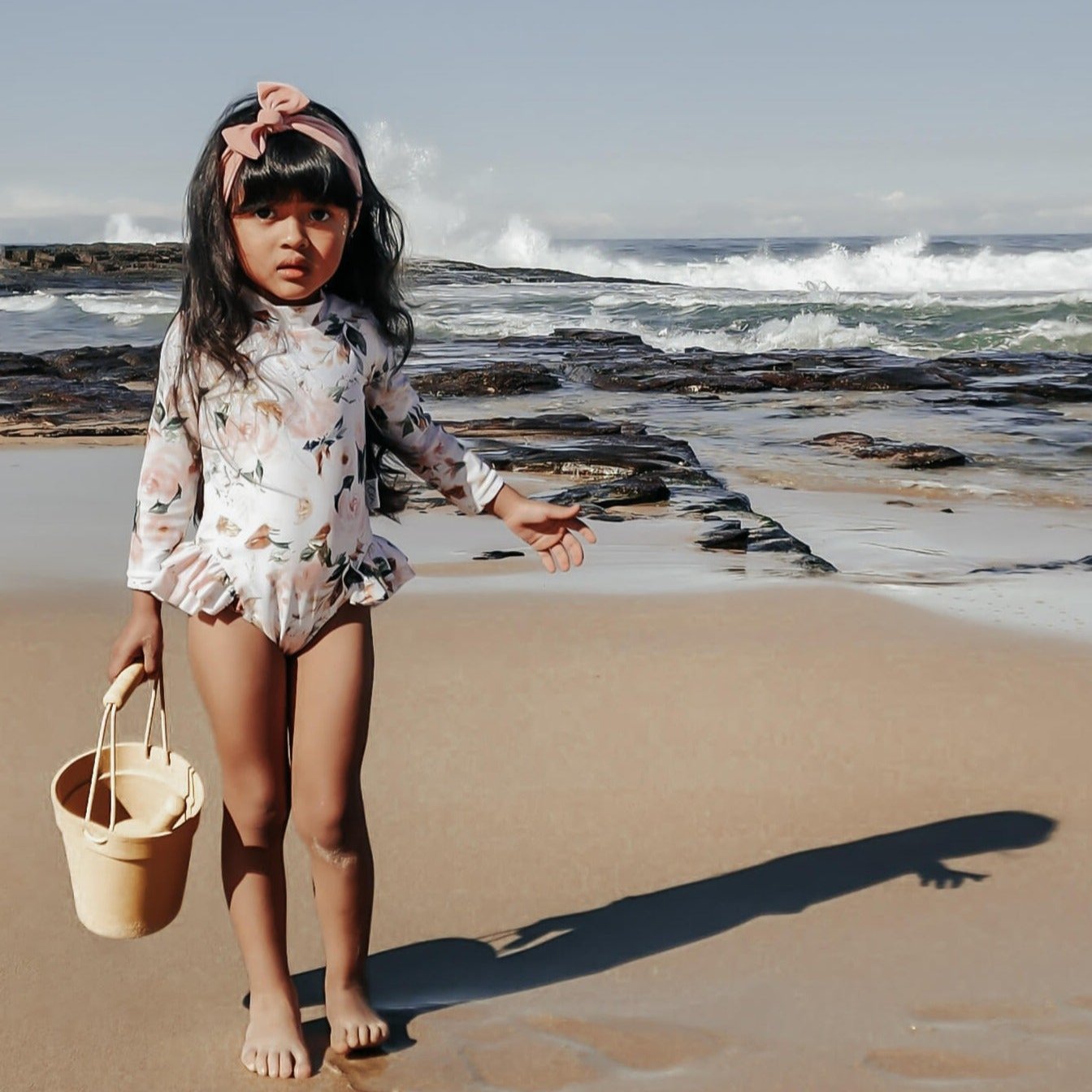 kids swimwear, young girl at the beach in a swimsuit with nappy changing snaps