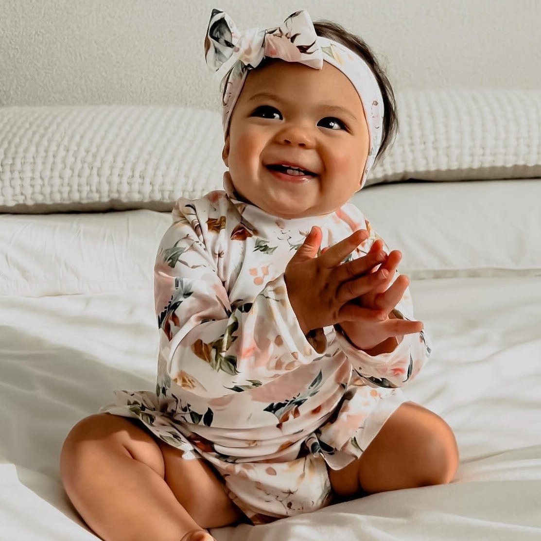 baby girl wearing a swimsuit with nappy change snaps and a matching headband