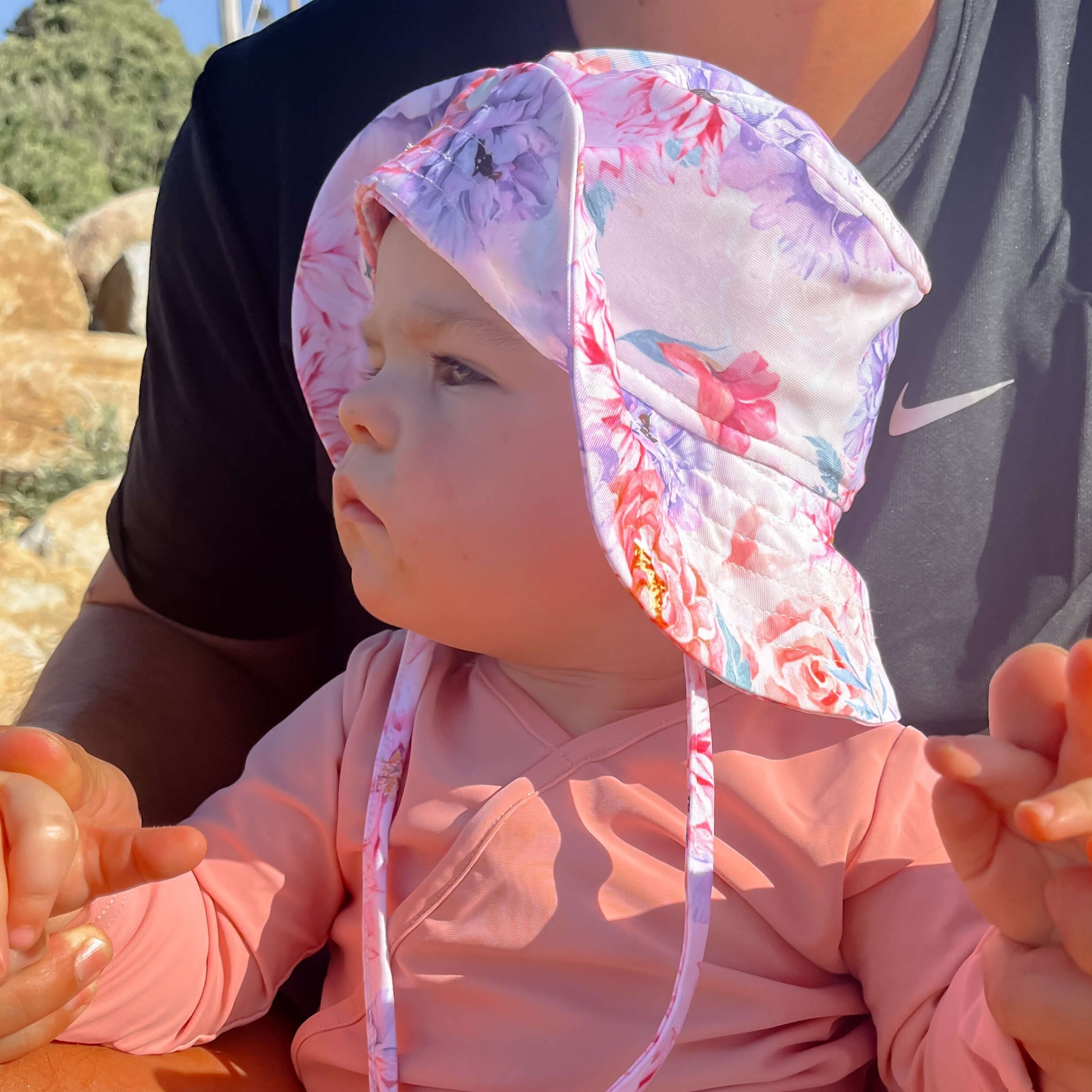 Baby girl on the beach with her dad wearing a sun hat