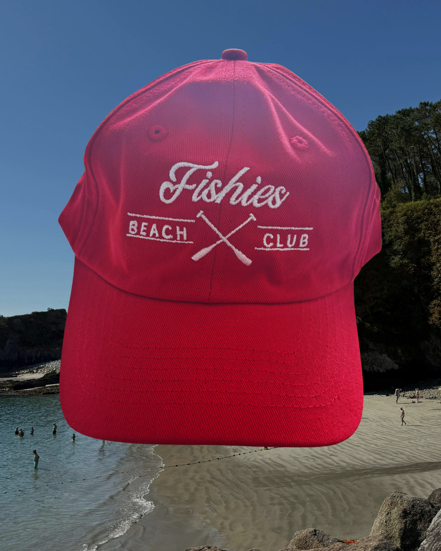 Red cap with 'Fishies Beach Club' logo on a beach background