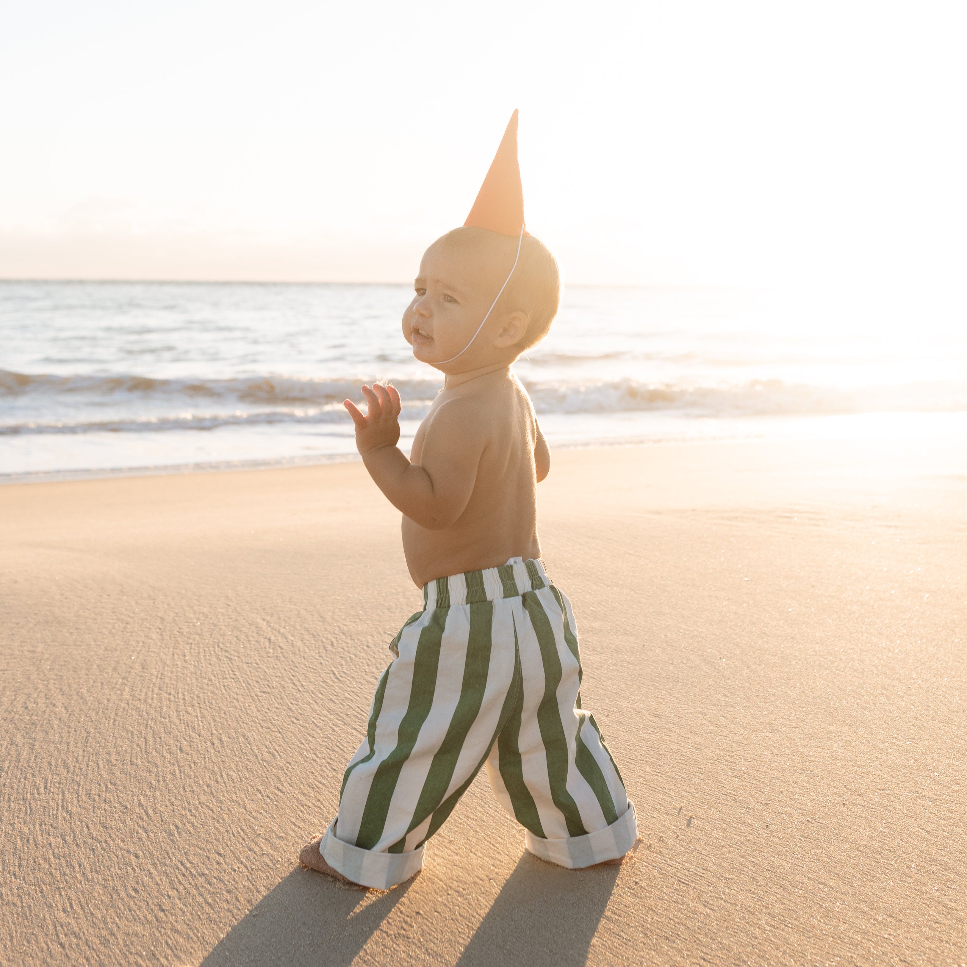 infant beach wear baby and toddler boys green and white striped pants walking on the beach