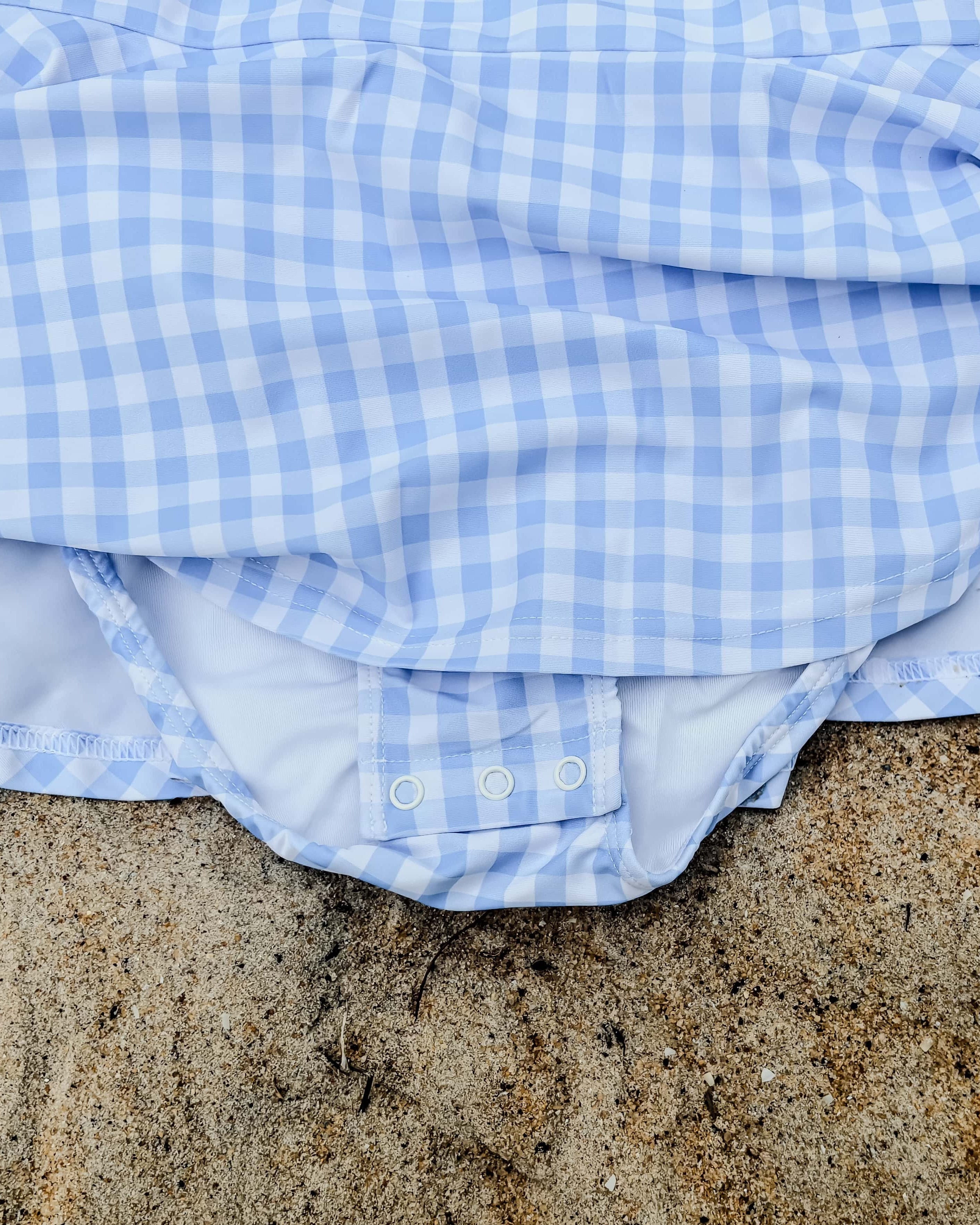 Blue and white swim dress on sandy ground with nappy change snaps