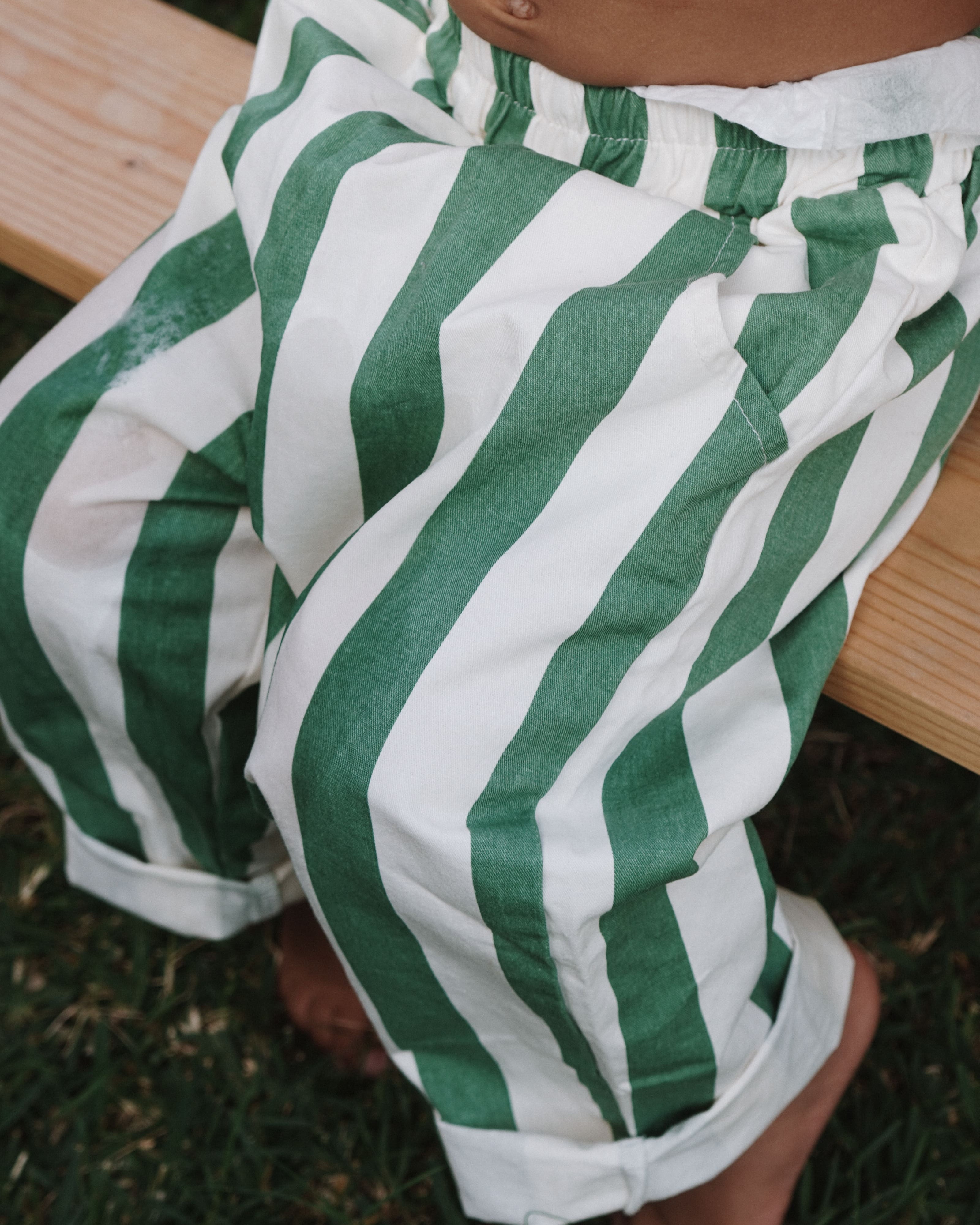 Green and white striped pants worn by a child on grass