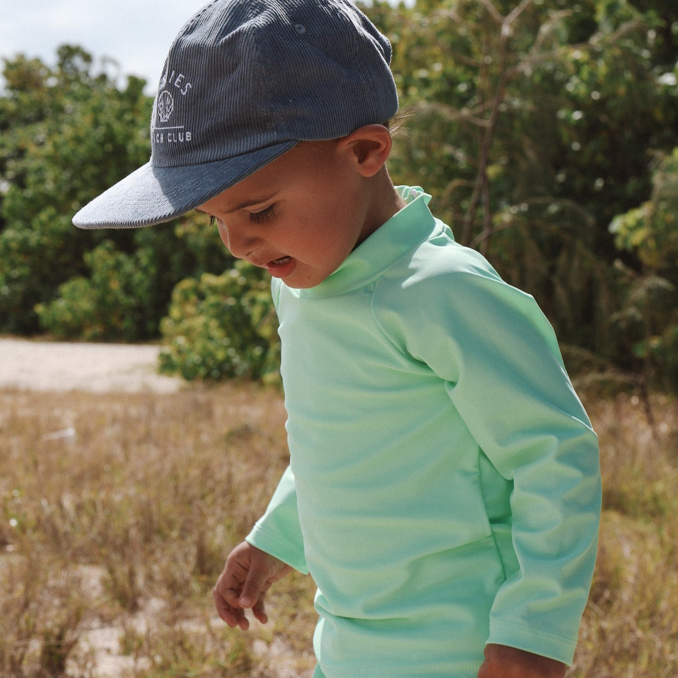 Child wearing a bright high vis swim top green outfit and cap outdoors