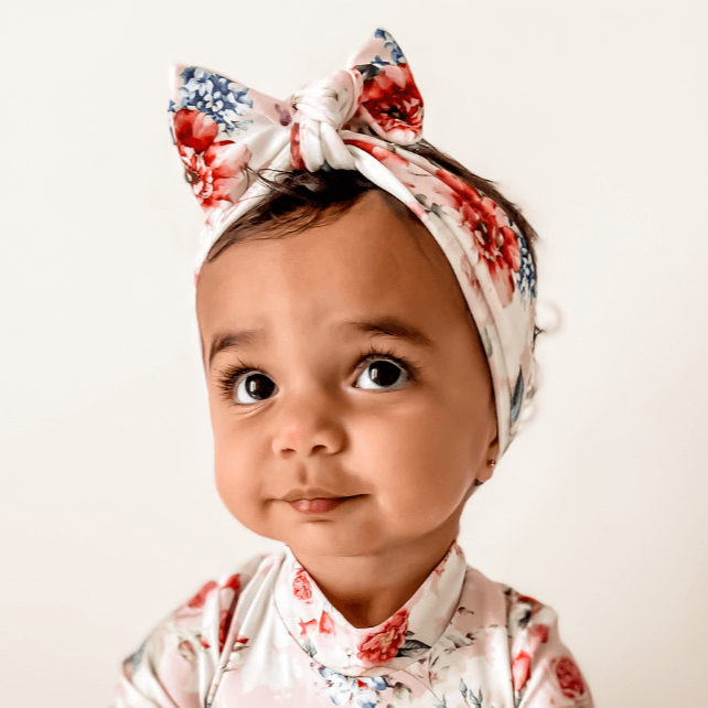 baby girl wearing a floral premium nappy change snap swimsuit with matching headband