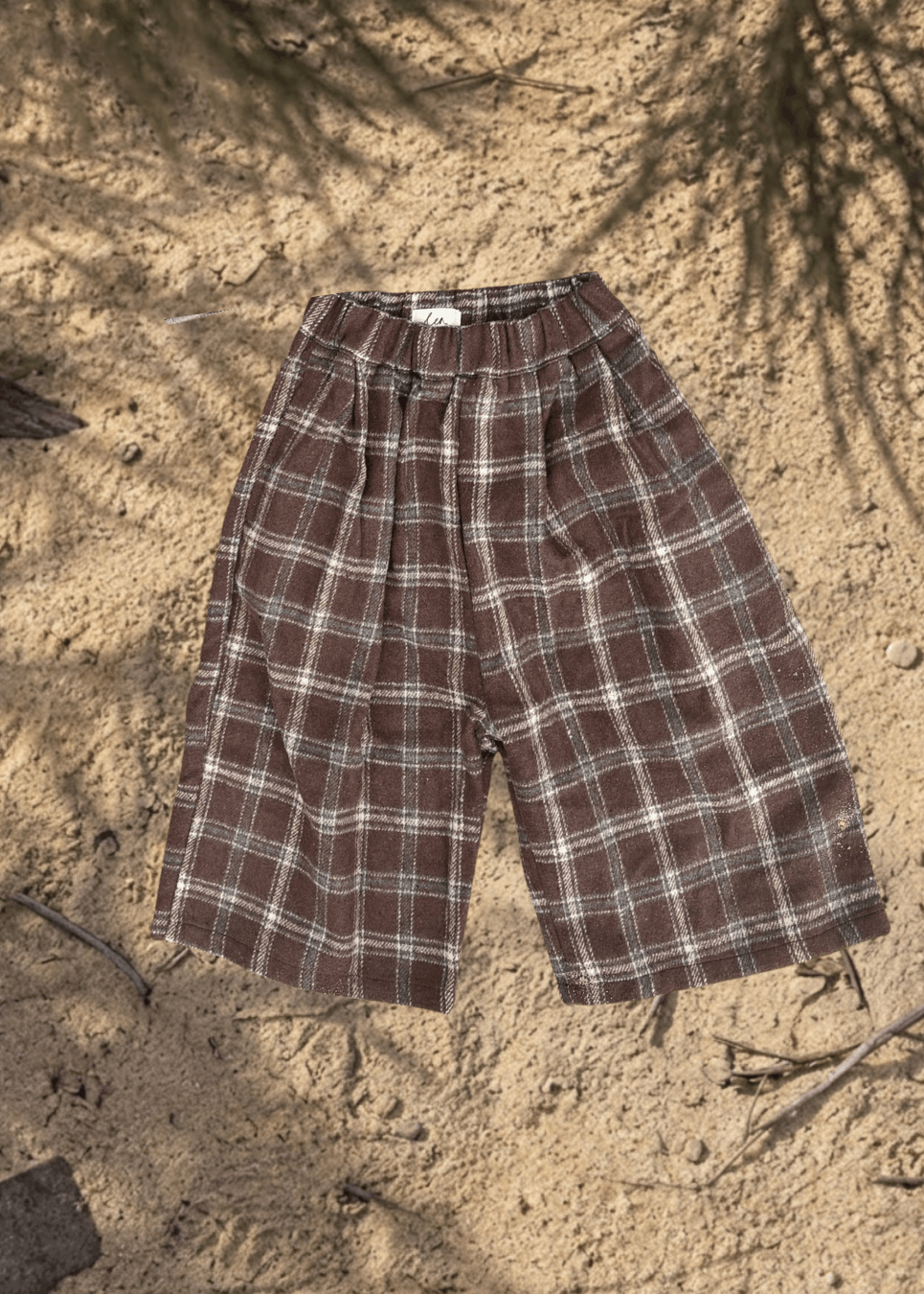 kids Brown plaid pants on a sandy surface