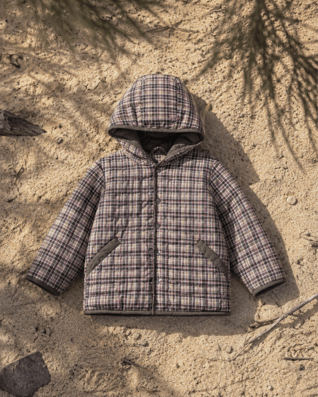 Plaid child and toddler jacket on sandy ground