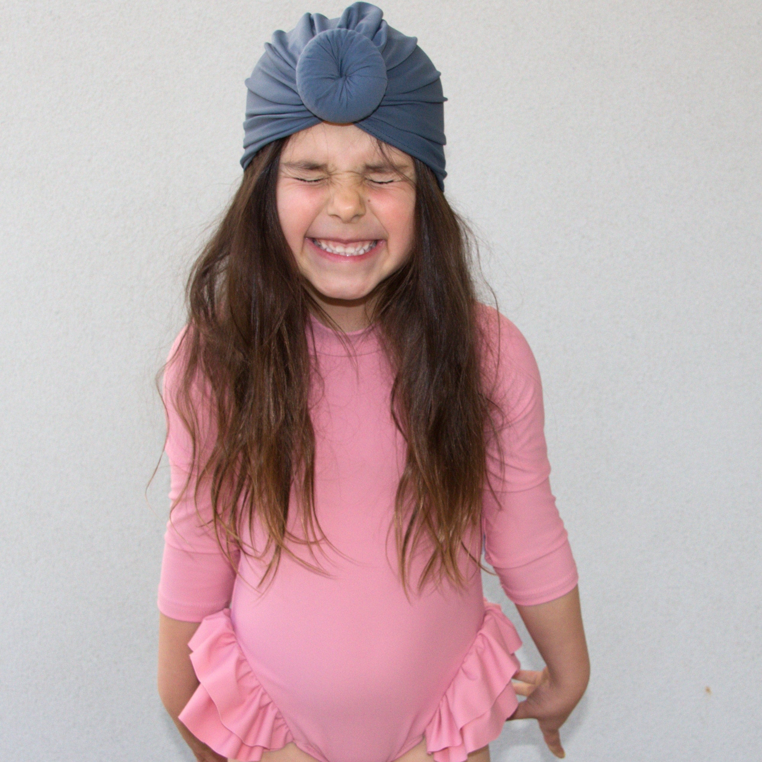 Little girl wearing prink swim suit and navy swim turban