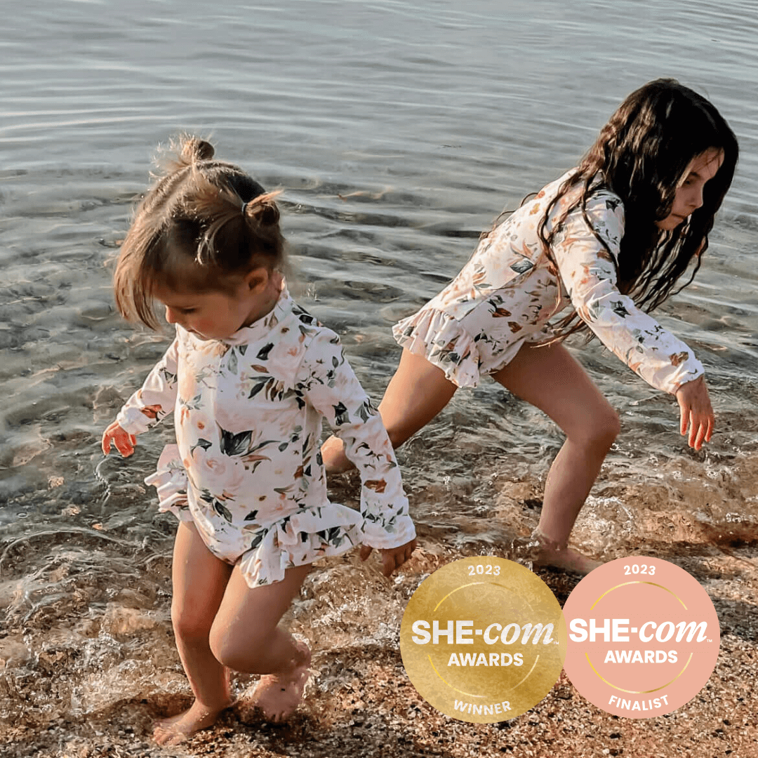 two girls in matching premium long sleeve nappy change snap swimsuits. Sizes for babies, toddler and girls.