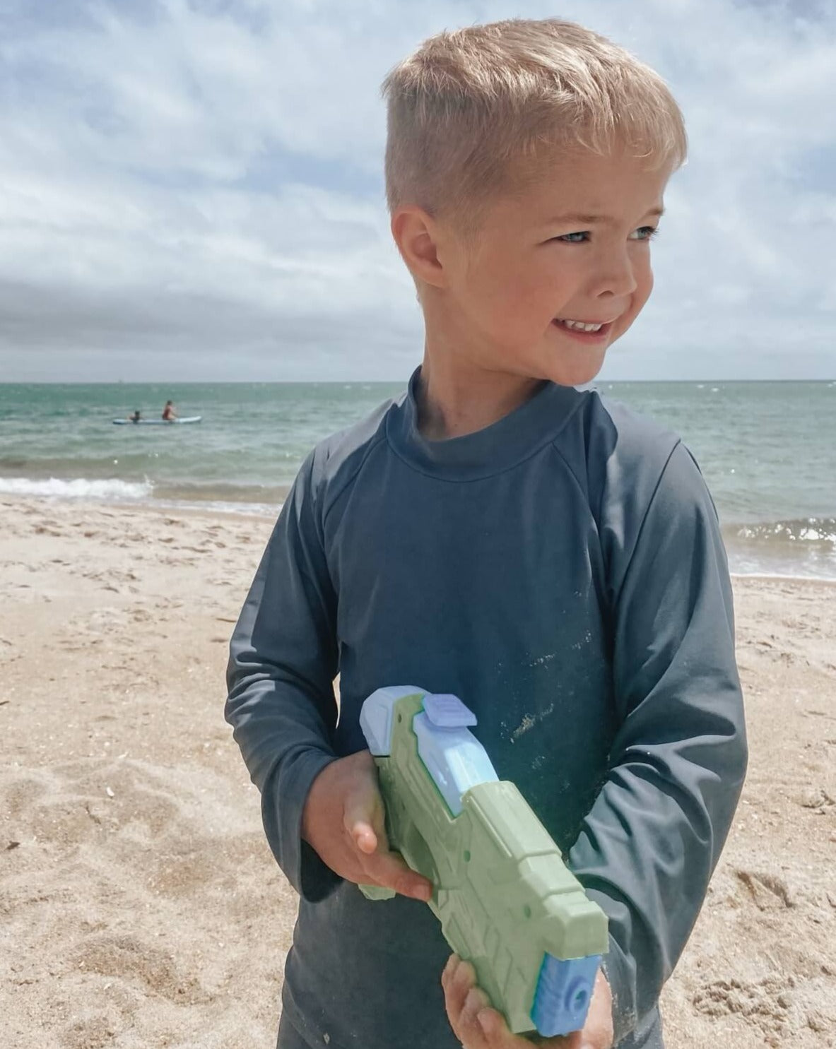 boy on beach wearing a blue rashguard for swimming