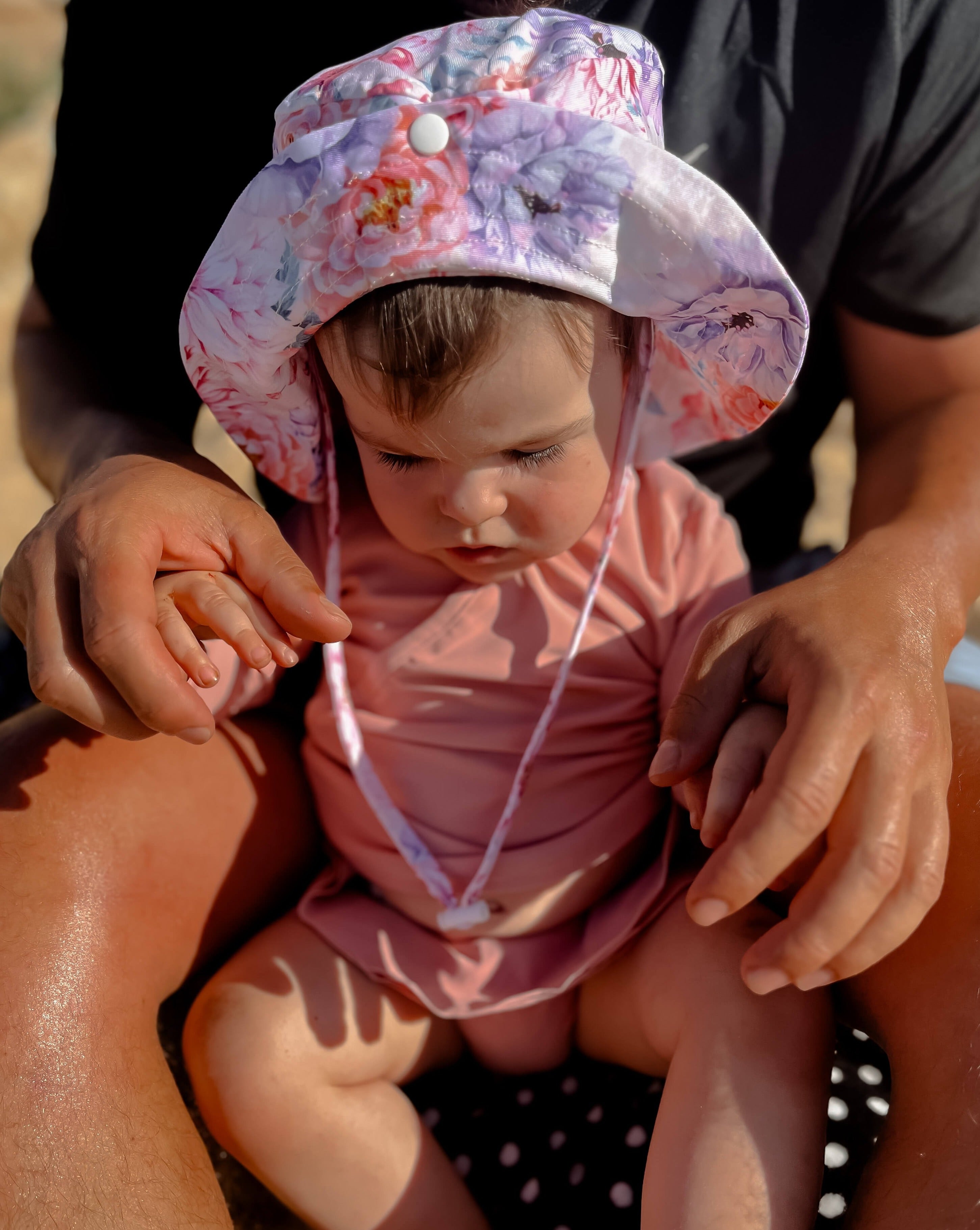 Baby girl wearing a pink rash vest set and swim hat