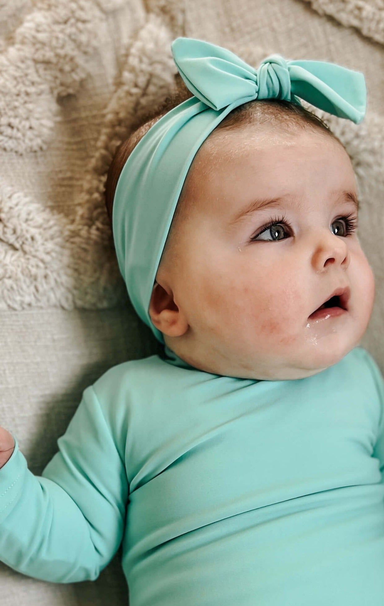 Baby girl in matching snap swimsuit and aqua green headband for in the water