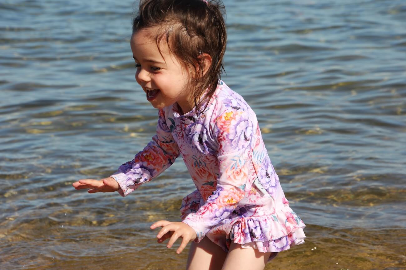 girl playing in the water wearing a floral ballerina style swimset