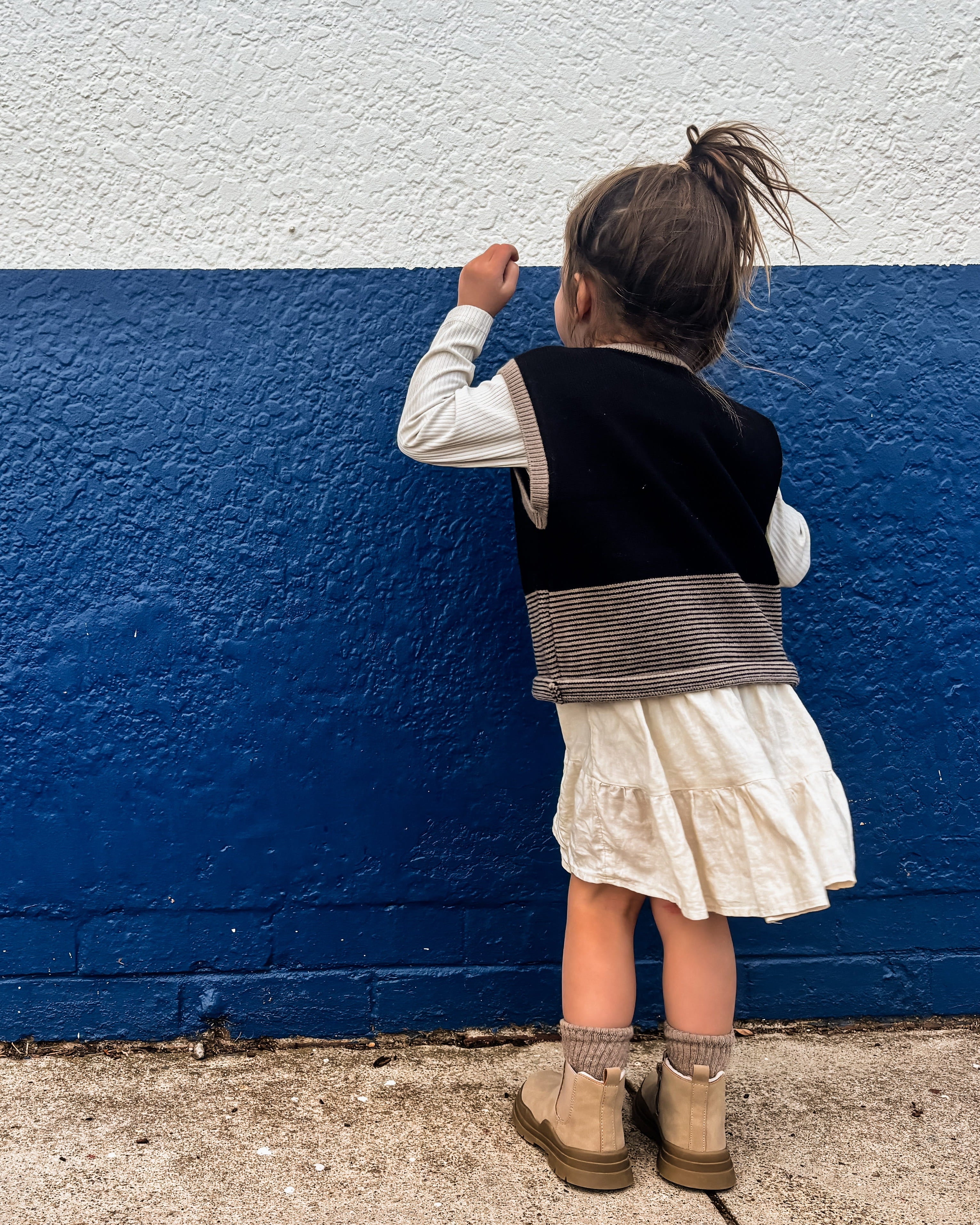 Child standing against a blue and white wall