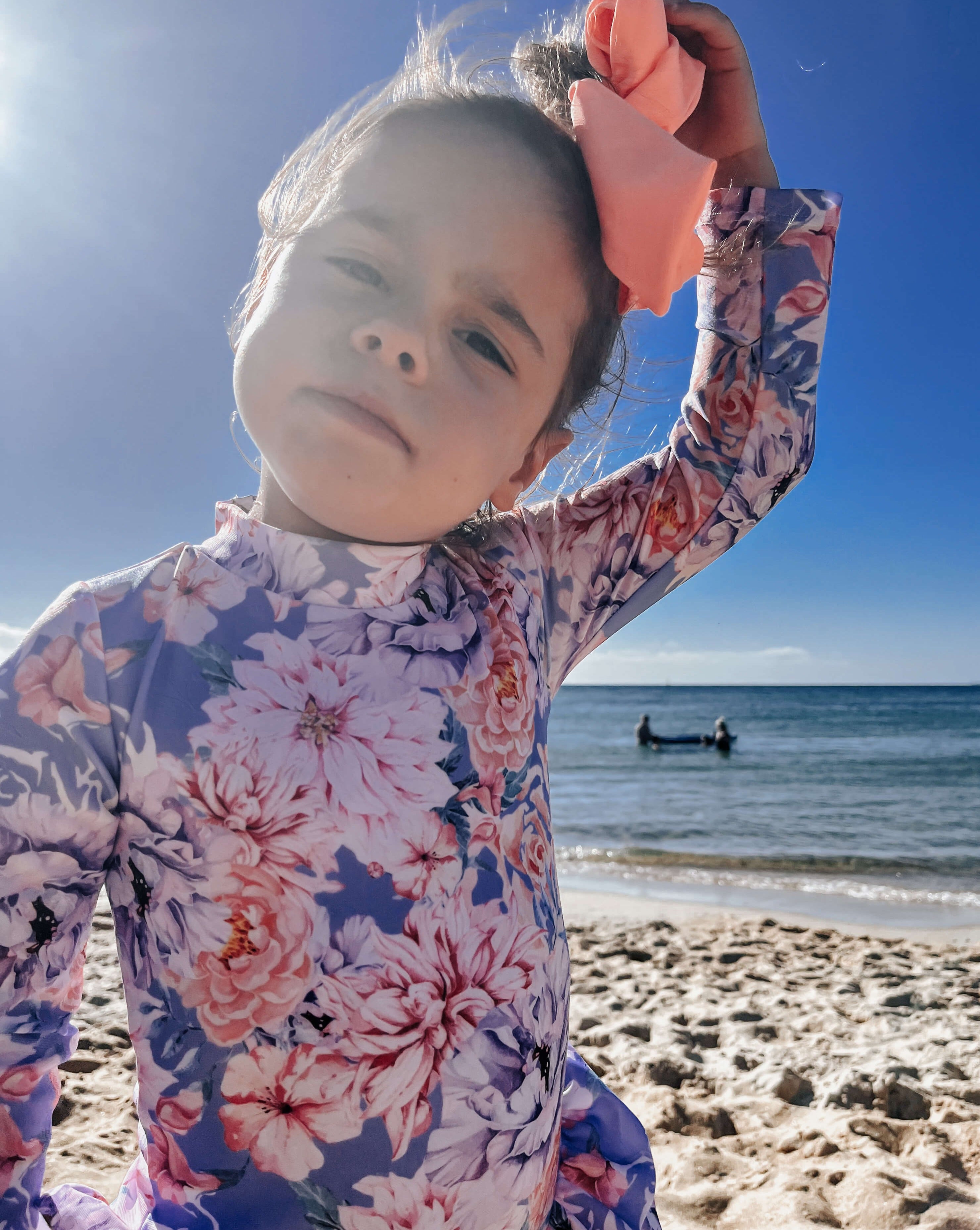 Toddler wearing the best long sleeve sun safe swimsuit with nappy change snaps in a blue and floral color