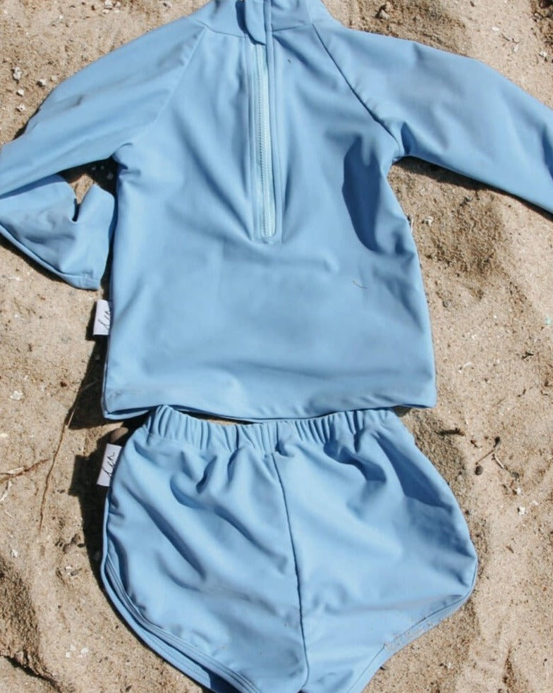A baby blue rash top and short set for kids with a large zip at the back