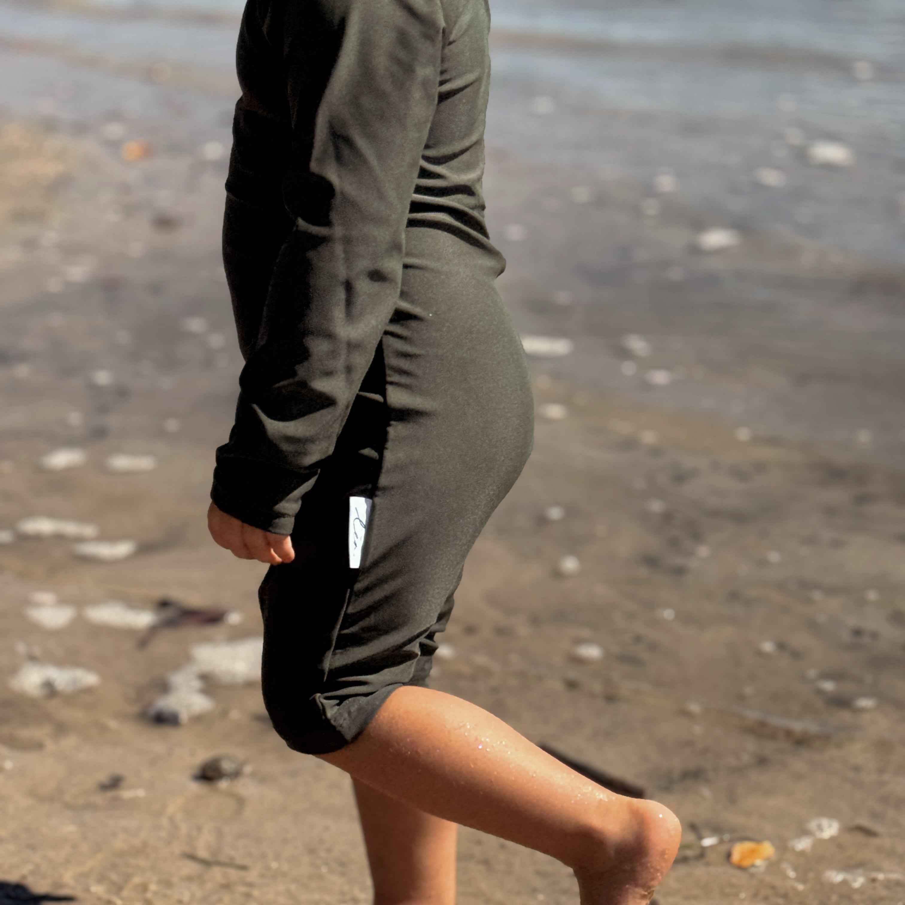 toddler wearing an all in one rashsuit that olive and has nappy change snaps