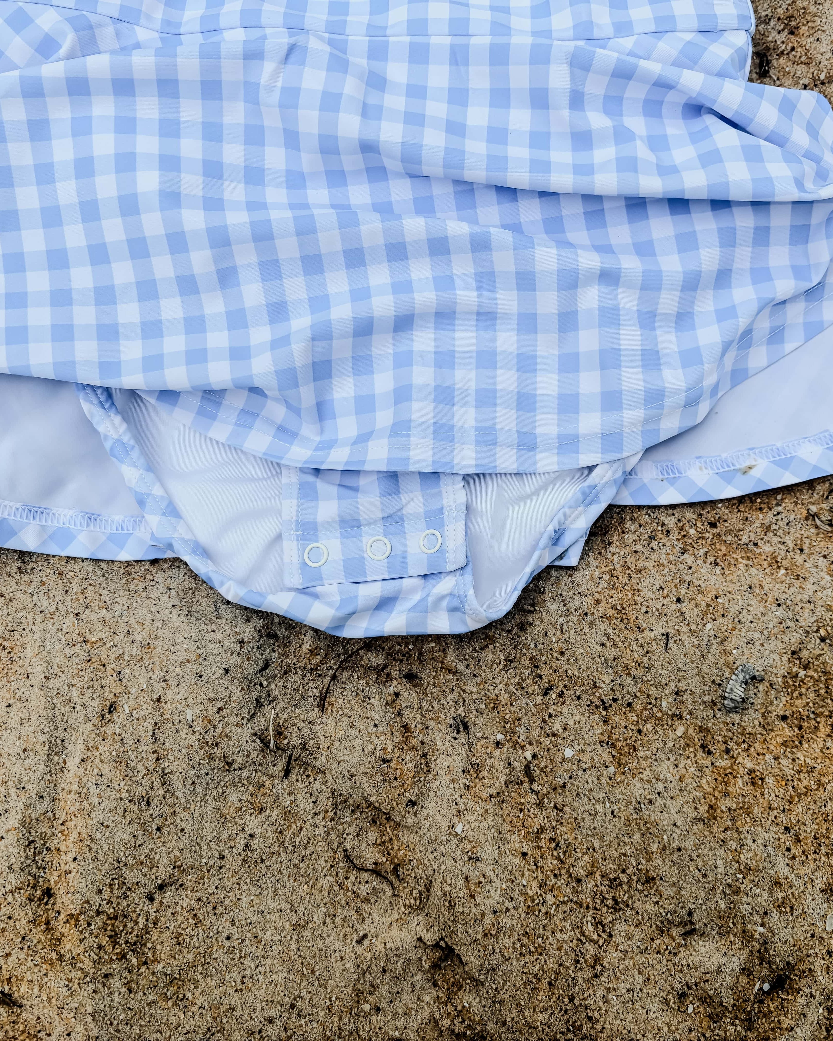 Blue and white swim dress on sandy ground with nappy change snaps