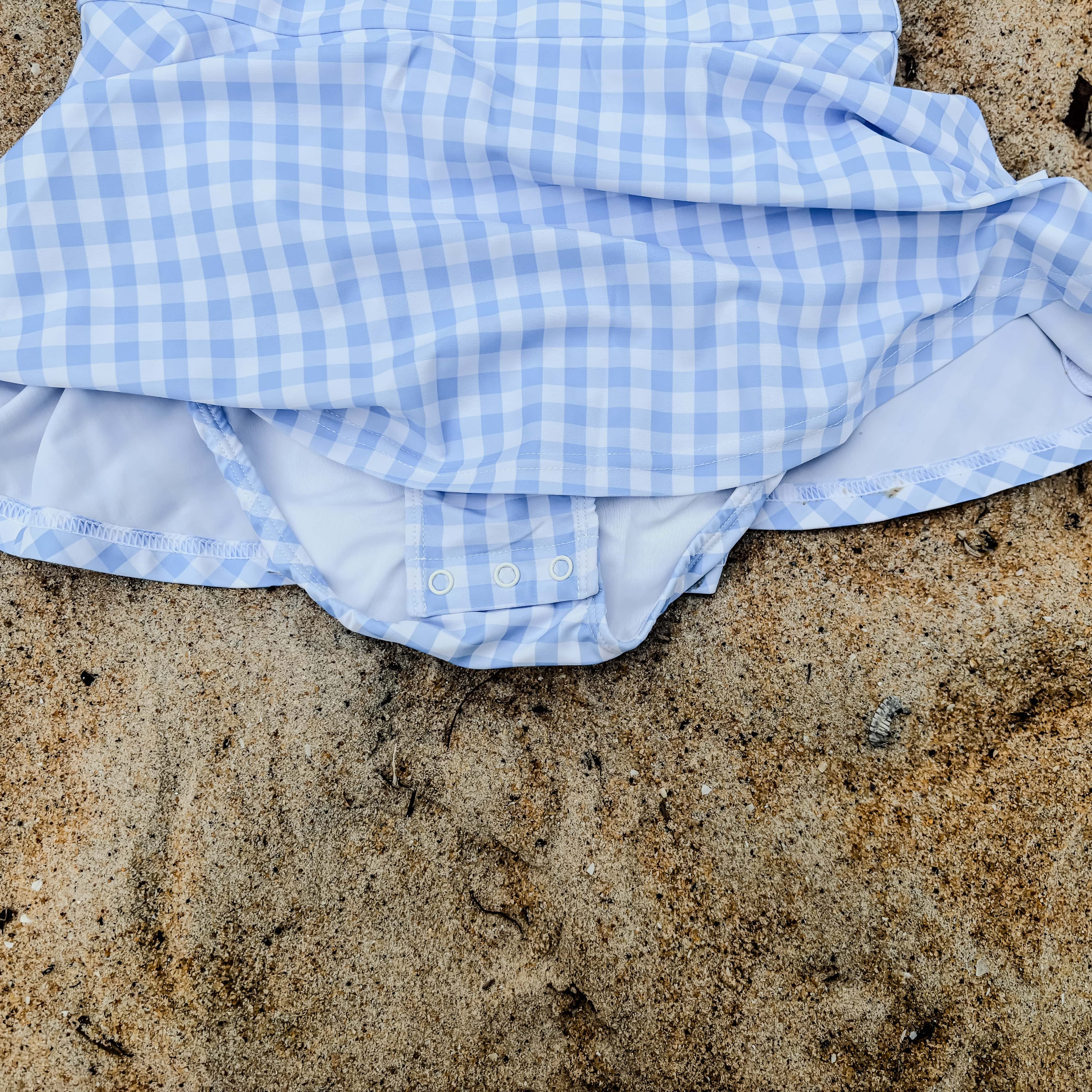Blue and white swim dress on sandy ground with nappy change snaps