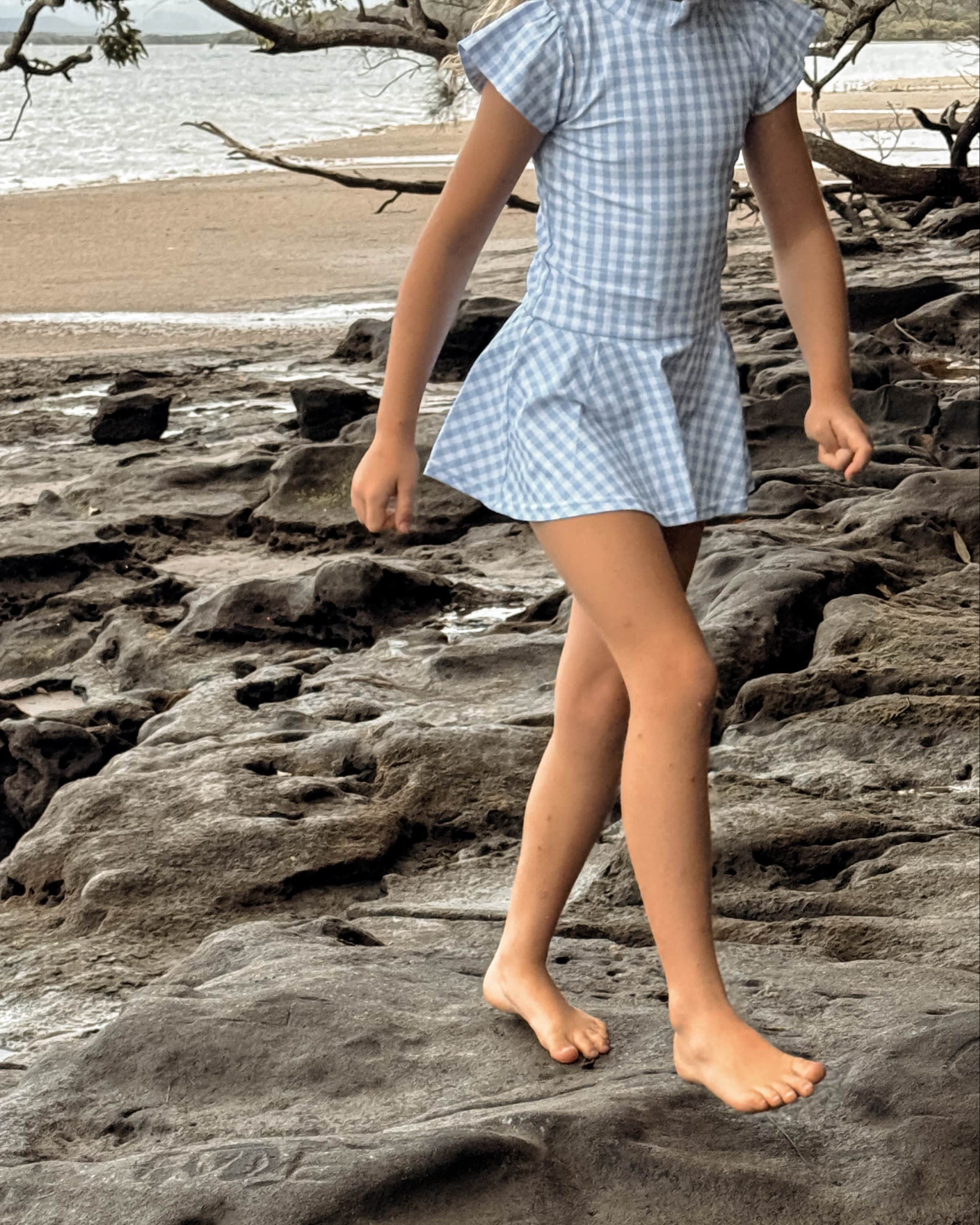 girls in a snap change swim dress walking on rocks by a beach