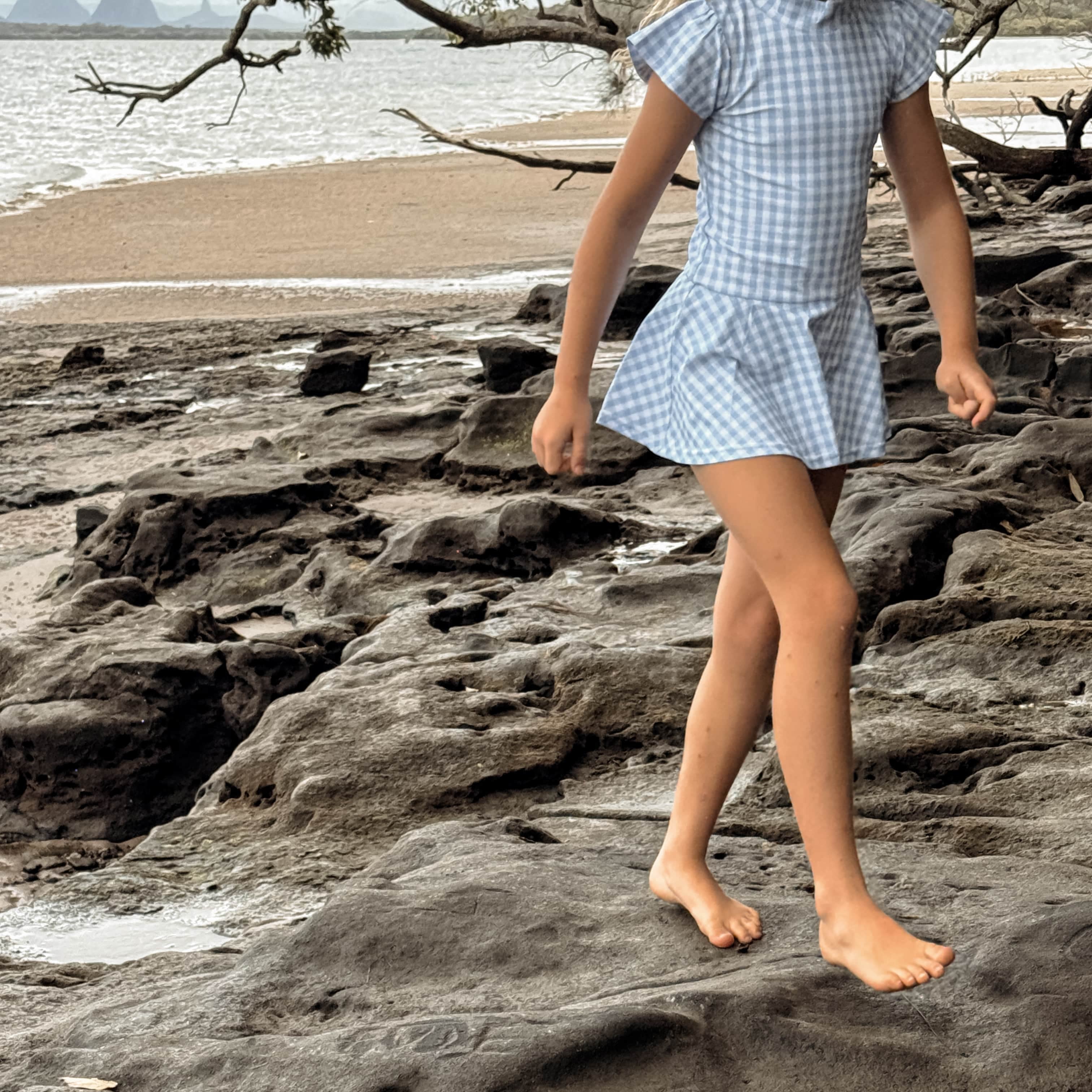 girls in a snap change swim dress walking on rocks by a beach