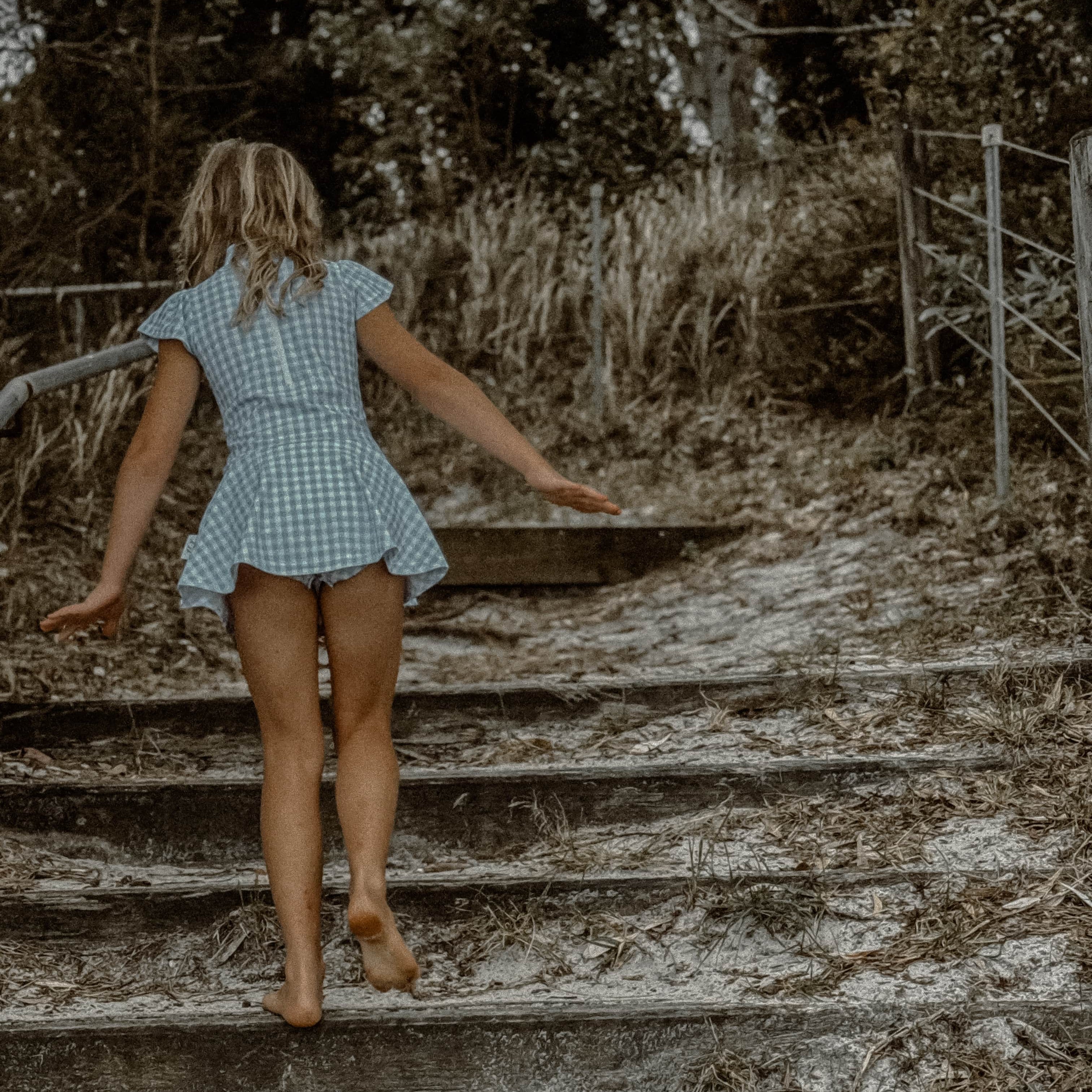 girls swimsuit in a checkered dress walking on wooden steps outdoors