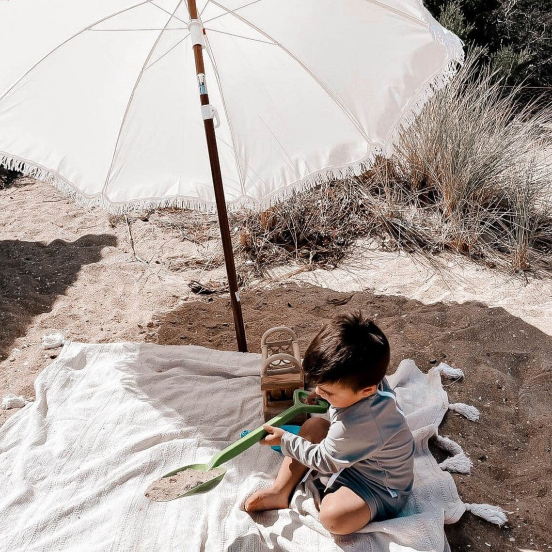 toddler  boy wearing a two piece swim set rash guard & short set in grey playing on the beach