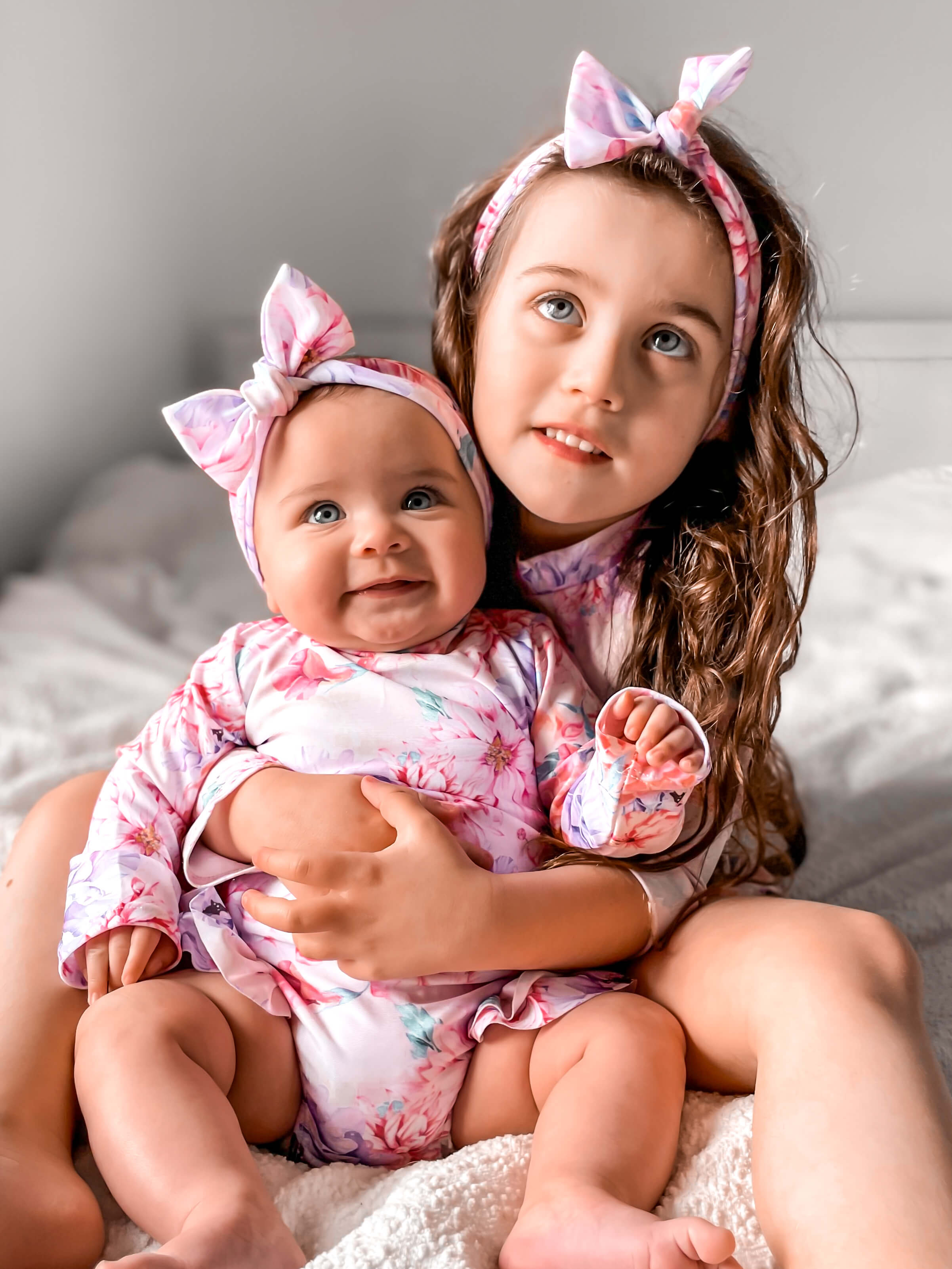 picture of baby girl and young sister wearing matching long sleeve swimsuits with nappy change snaps and matching water headbands. Children's swear Australian label Len Swim