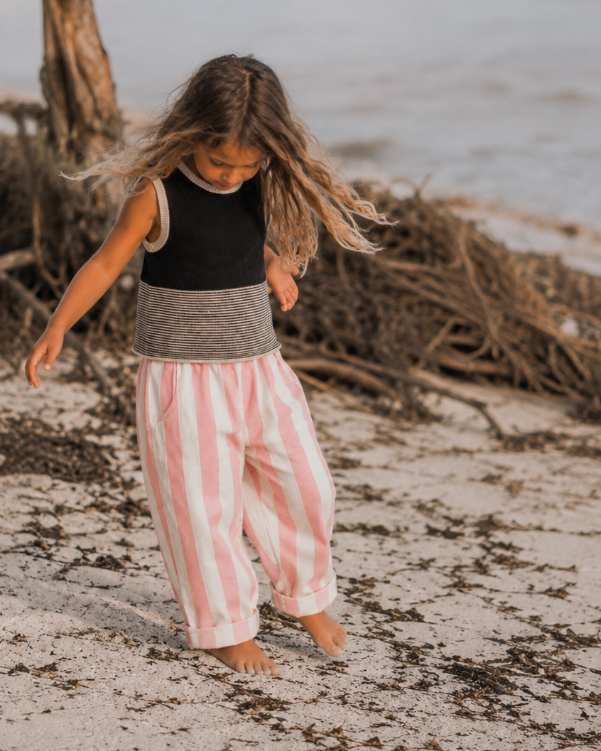 Child playing on a beach with driftwood and water in the background