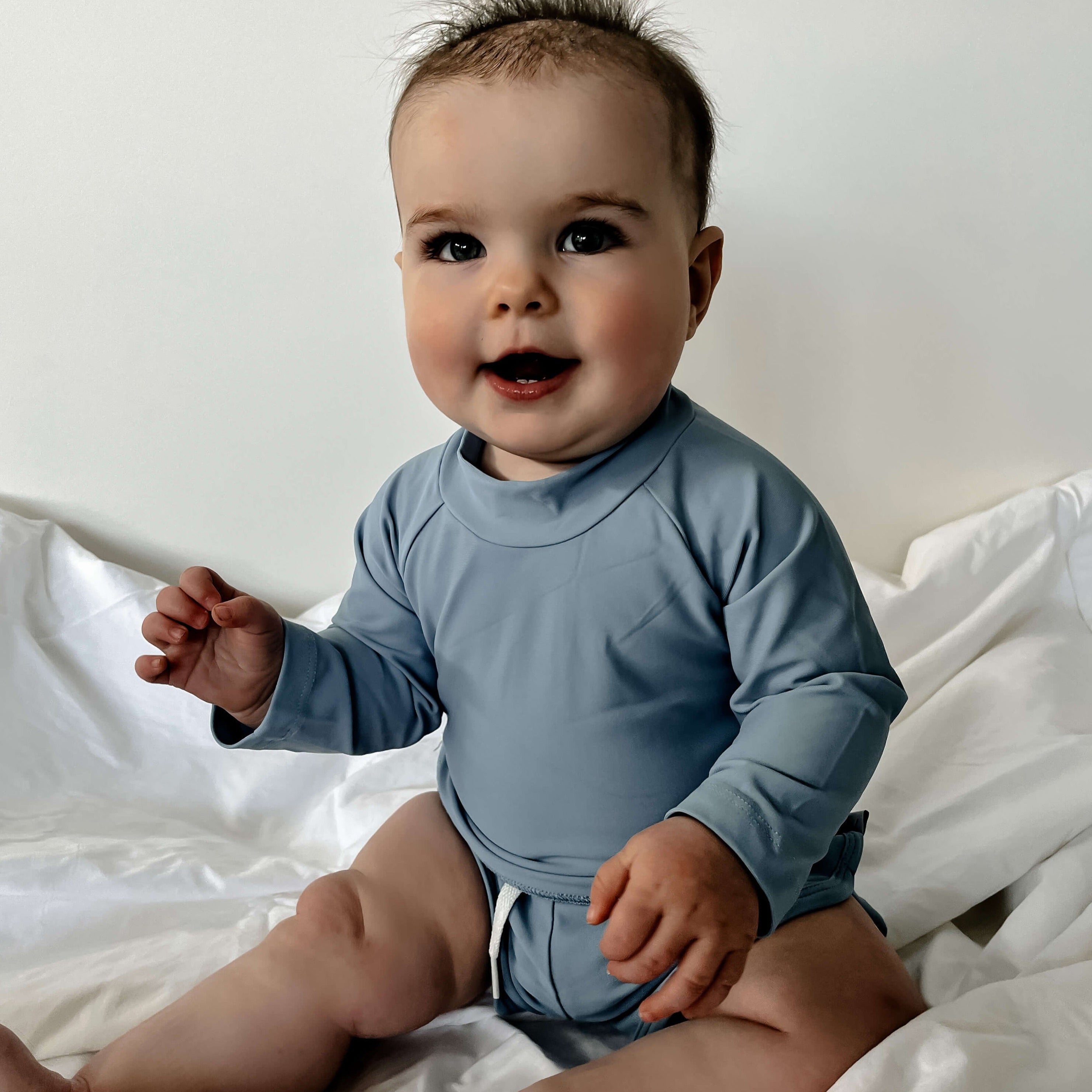 A baby boy wearing a swim set of rash guard and swim short