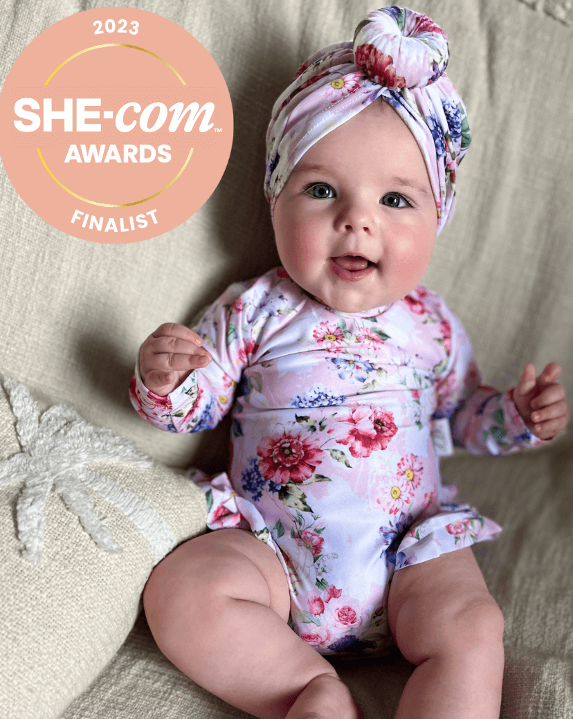 Baby girl wearing a floral nappy change swimsuit with matching headband swim turban