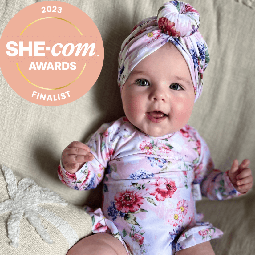Baby girl wearing a floral nappy change swimsuit with matching headband swim turban