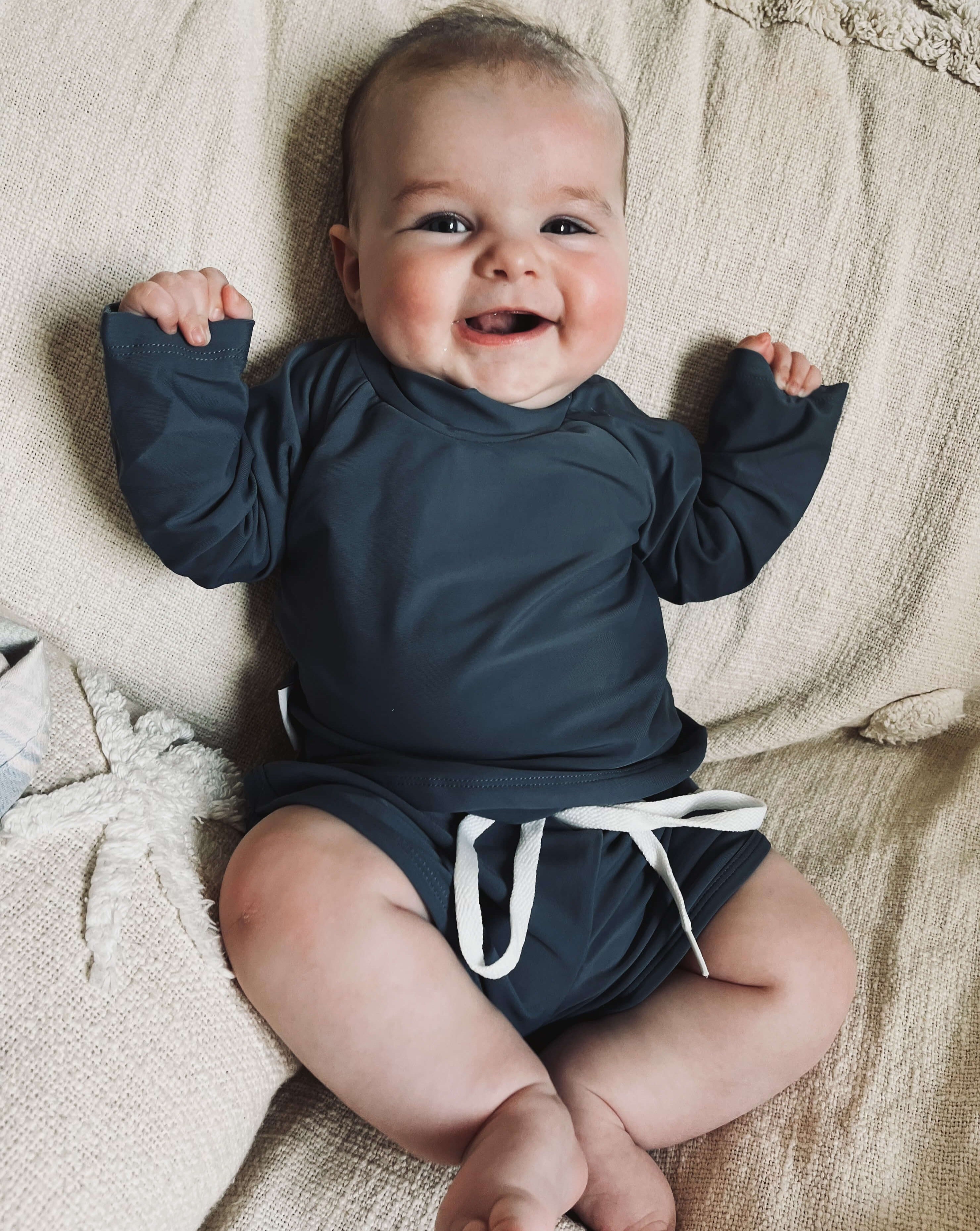 Baby boy wearing a two piece rash guard swim top and short set in navy. Sizes for newborn, toddlers and kids