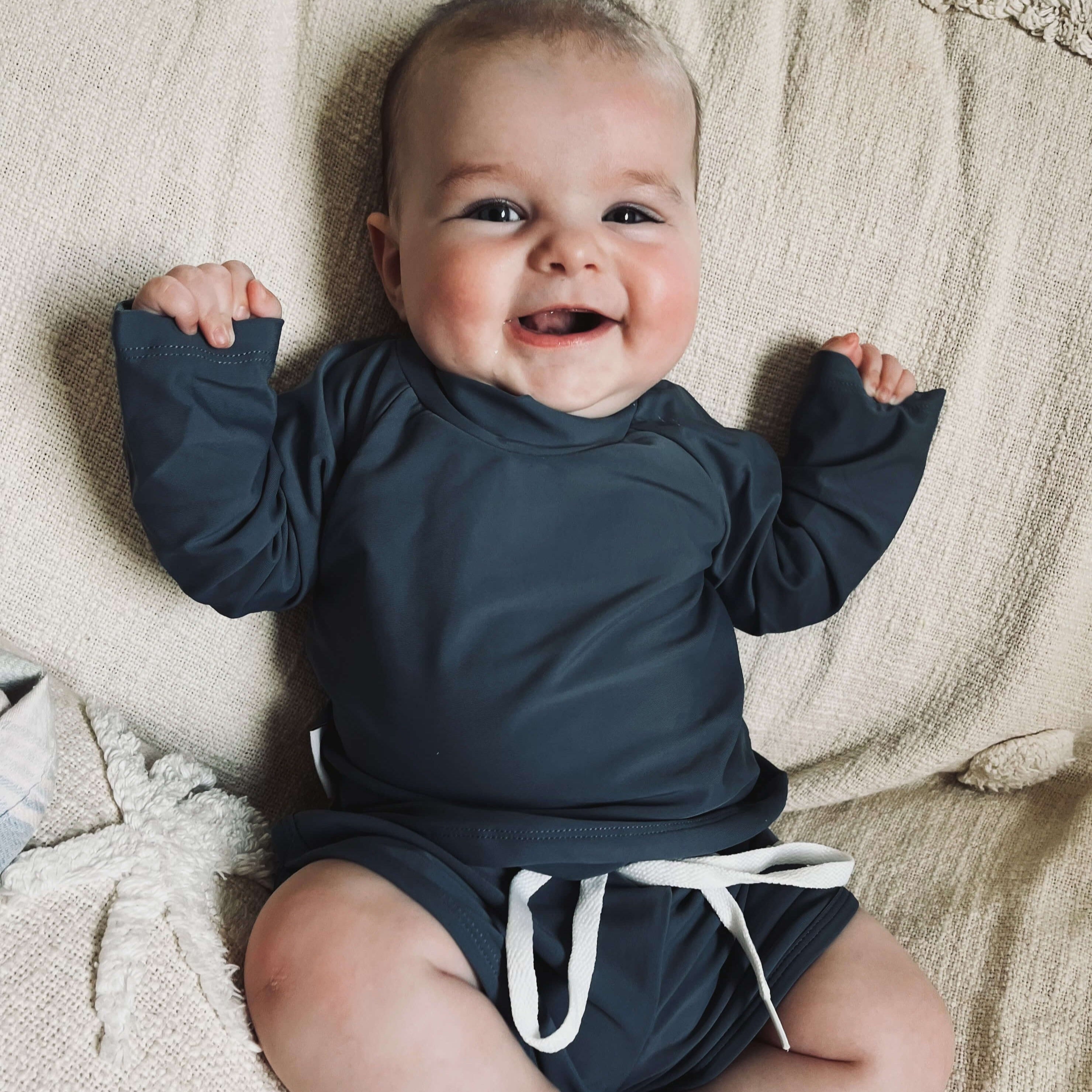 Baby boy wearing a two piece rash guard swim top and short set in navy. Sizes for newborn, toddlers and kids