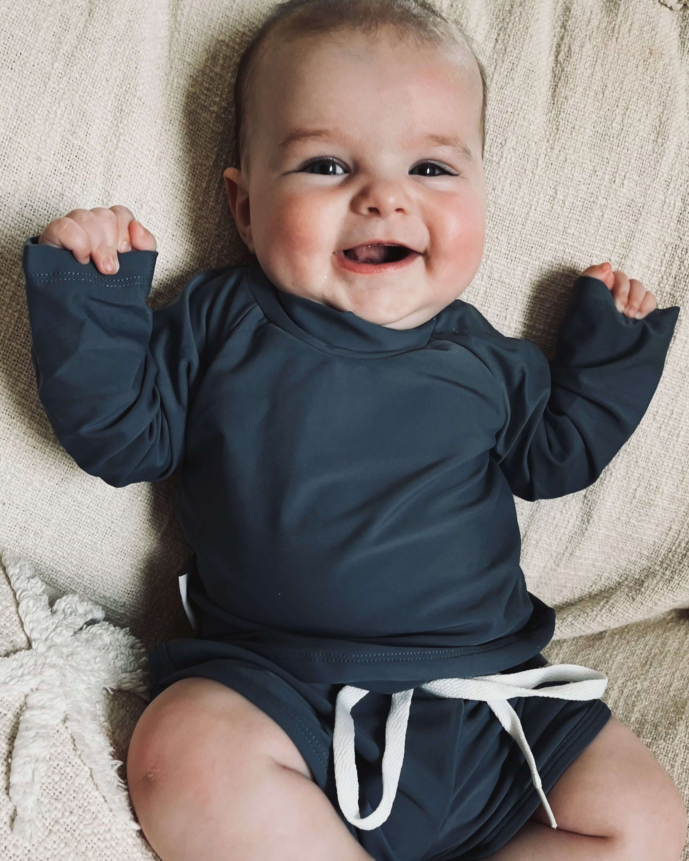 Baby boy wearing a two piece rash guard swim top and short set in navy. Sizes for newborn, toddlers and kids