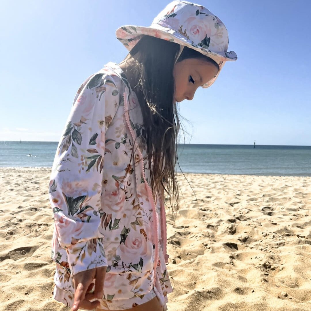 Young girl wearing matching swimming dress with snaps, jacket and swim hat in floral