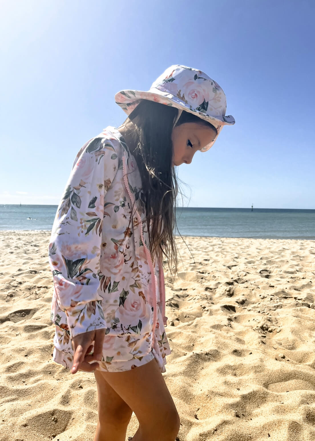 Young girl wearing matching swimming dress with snaps, jacket and swim hat in floral