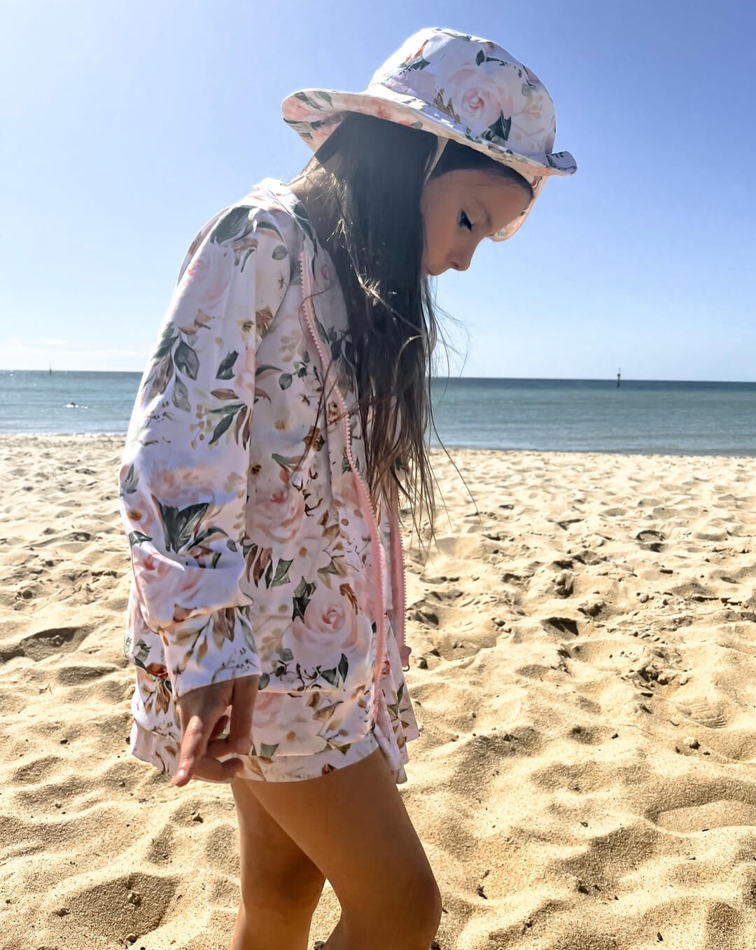 girl at beach wearing sun swim hat and swim dress with matching jacket