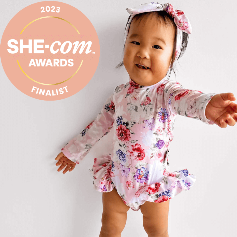 Toddler girl in long sleeve nappy change premium swimsuit and headband