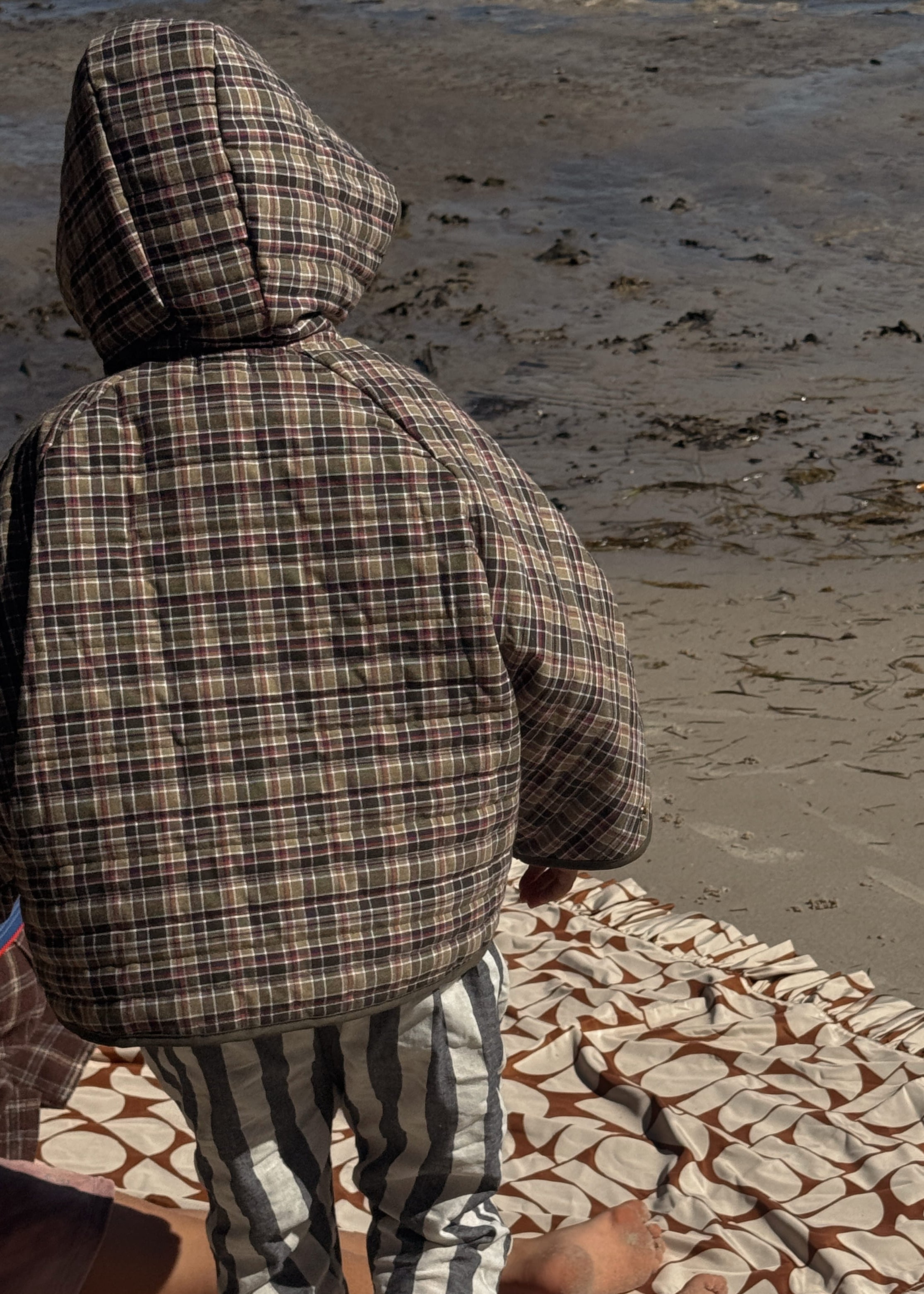 Person sitting on a textured blanket on a sandy beach