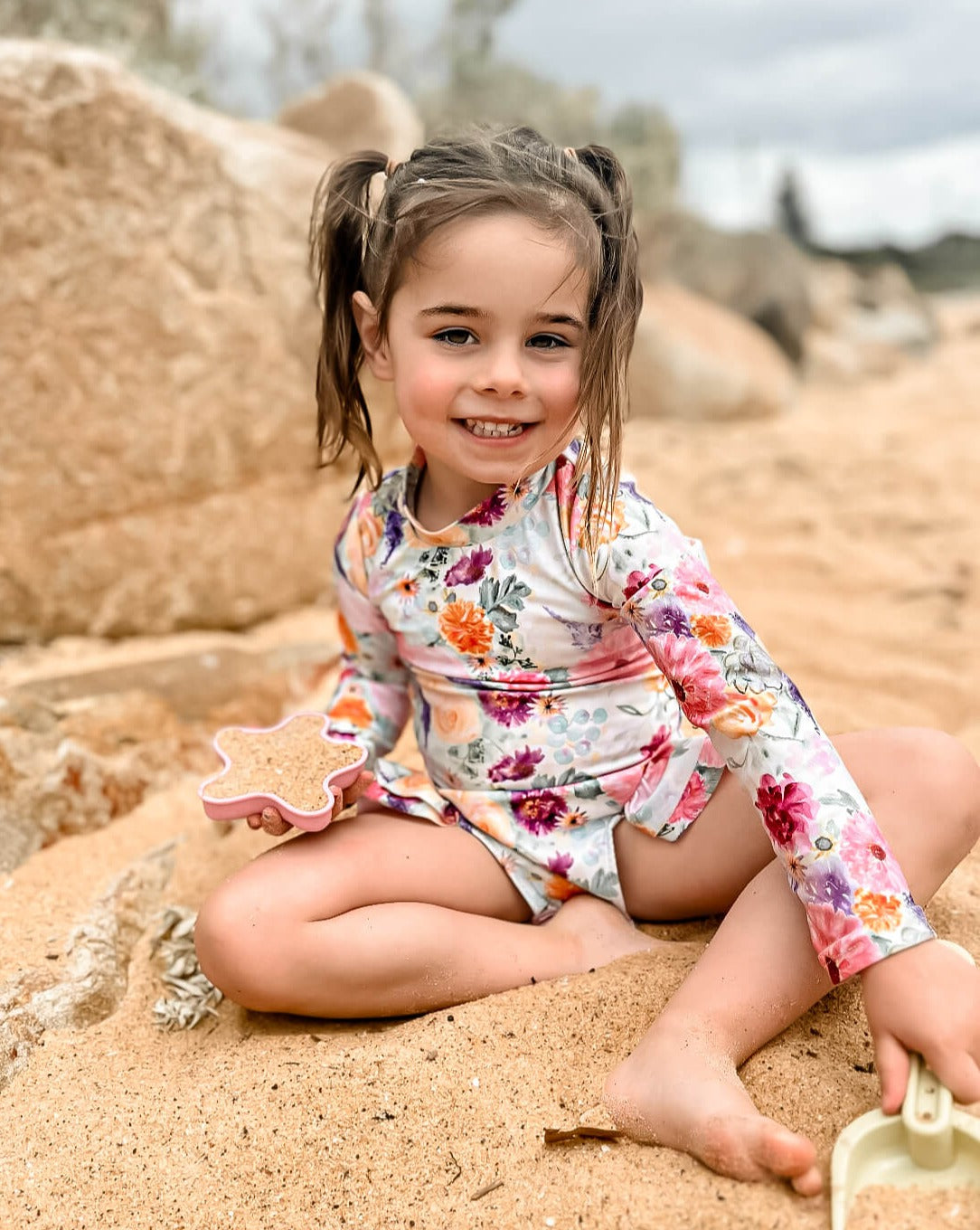 Young girl wearing a nappy change swimsuit with snaps in a bright floral pattern