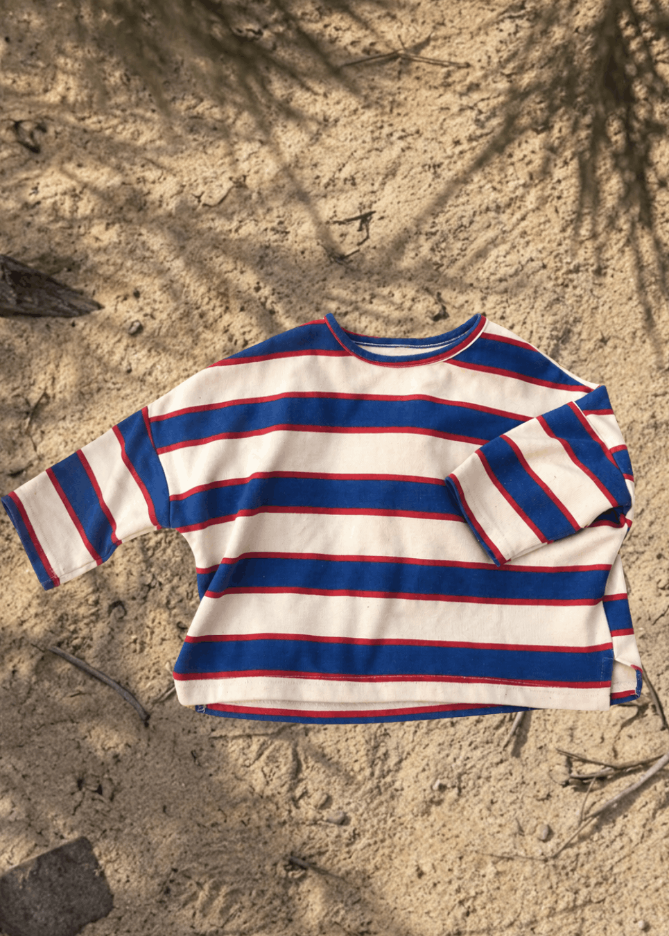 Striped kids long-sleeve shirt on sandy ground