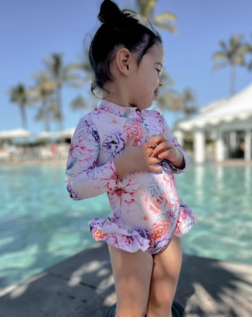 Young girl at a pool wearing floral long sleeve nappy change swimsuit