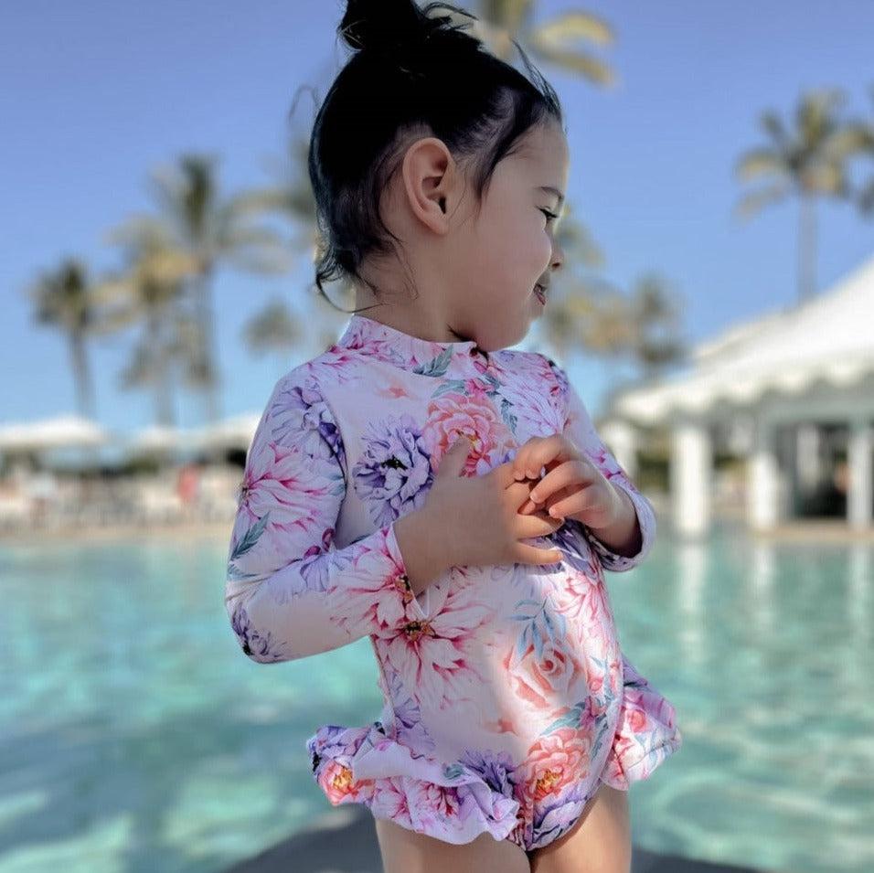 Young girl at a pool wearing floral long sleeve nappy change swimsuit