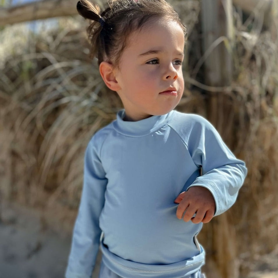 Little girl in rash set playing at the beach