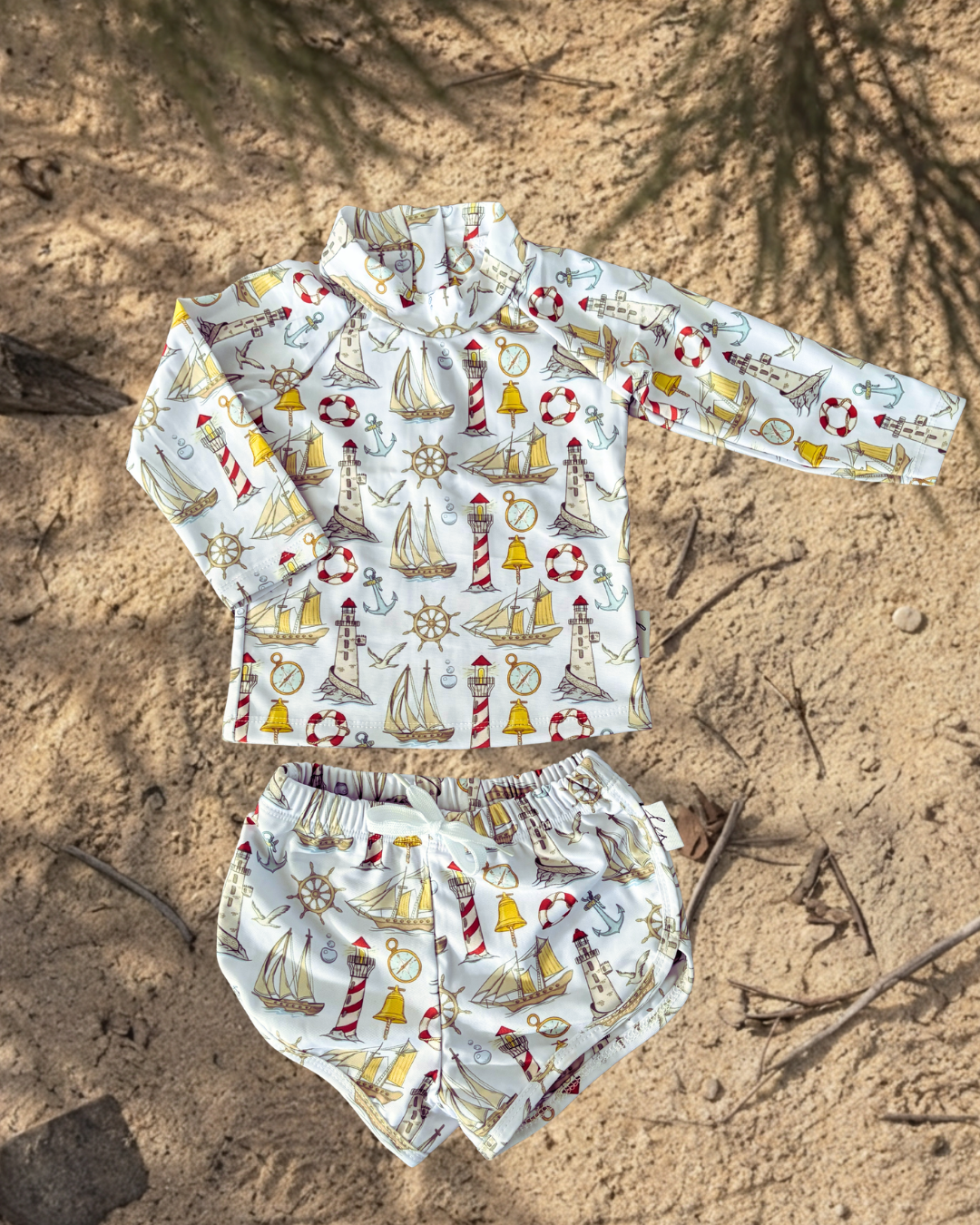Children's nautical-themed rash shirt and shorts set on sandy ground