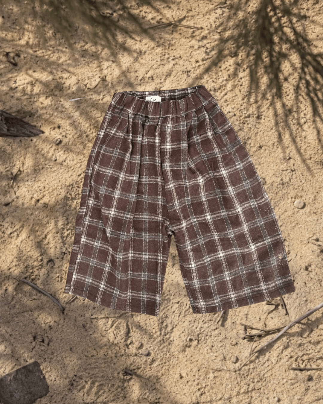kids Brown plaid pants on a sandy surface