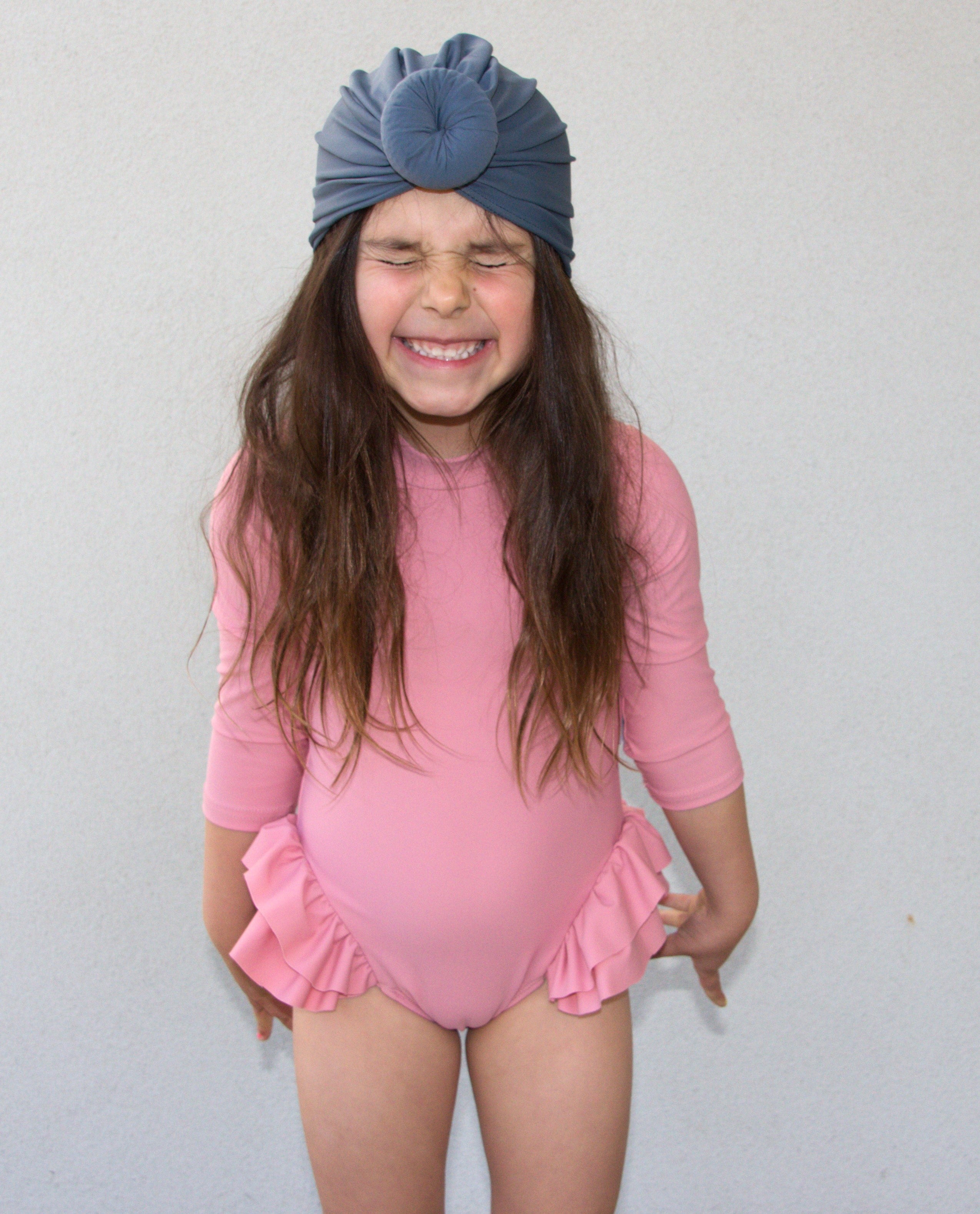 Little girl wearing prink swim suit and navy swim turban